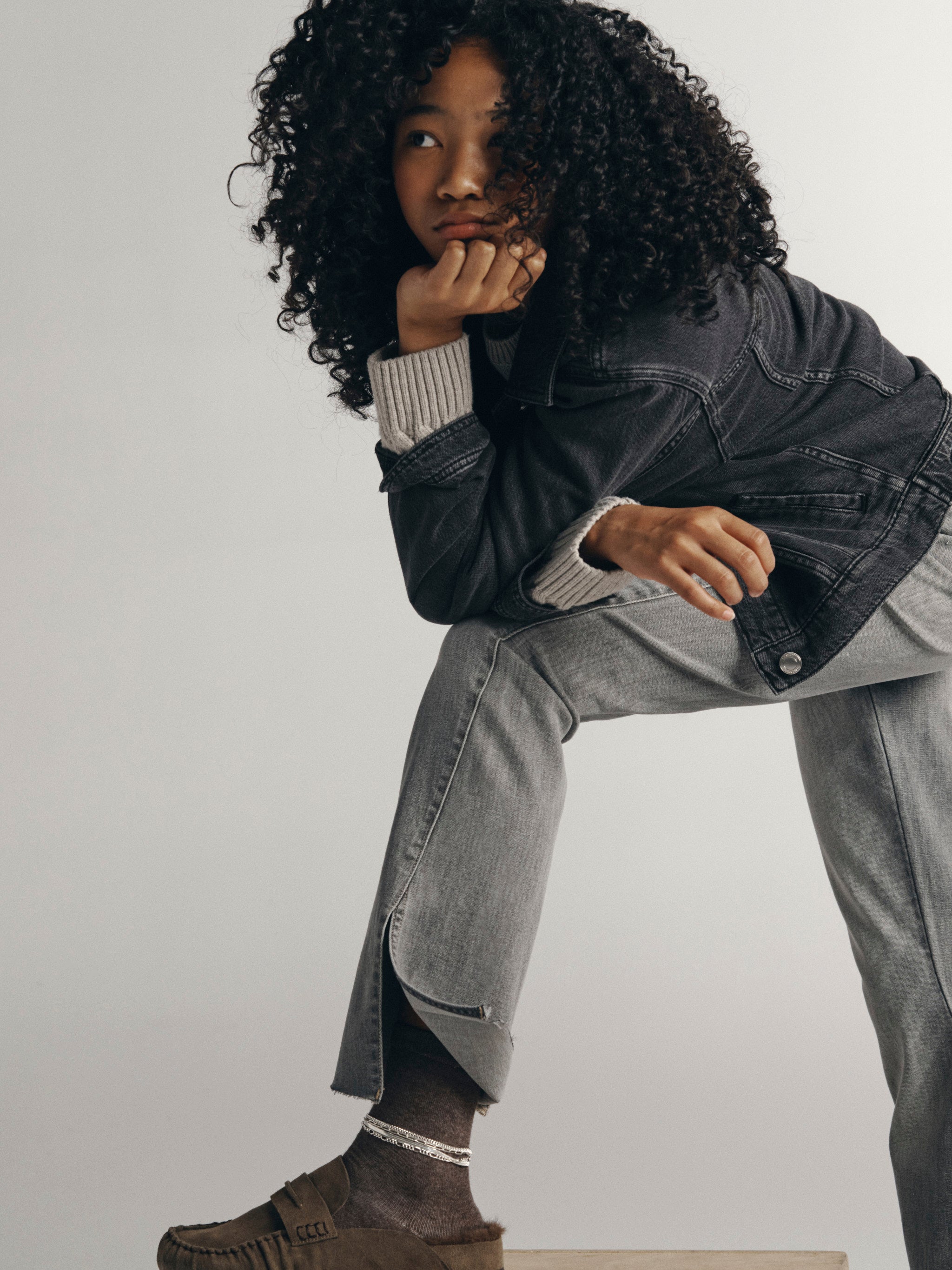 DL1961 Kids girls' Claire bootcut jeans in Twister with a grey Jordyn trucker jacket, seated three-quarter view in a studio.