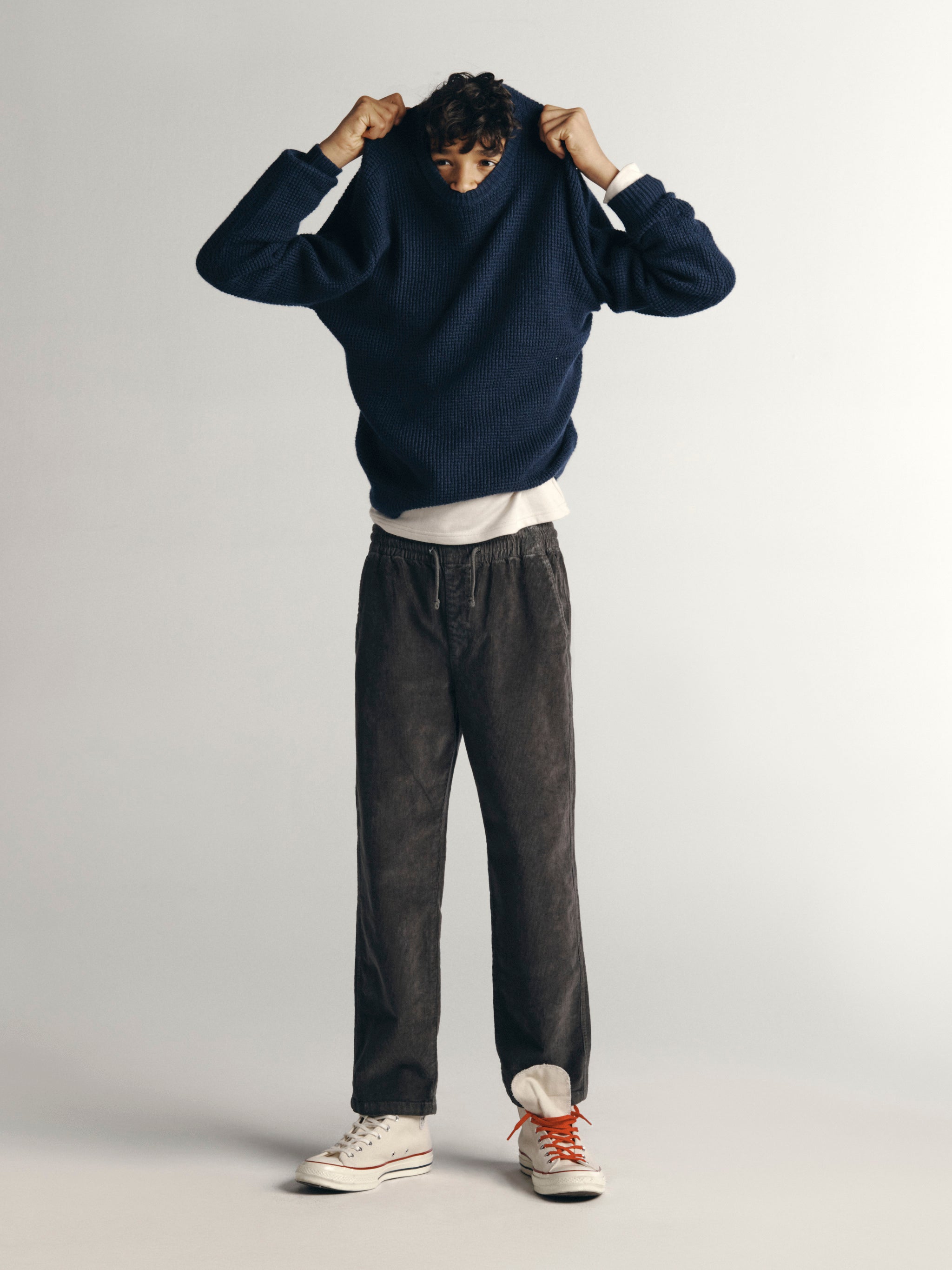 DL1961 Kids boys' Quentin corduroy joggers in Graphite with a navy sweater over a white tee, full-length front, studio.