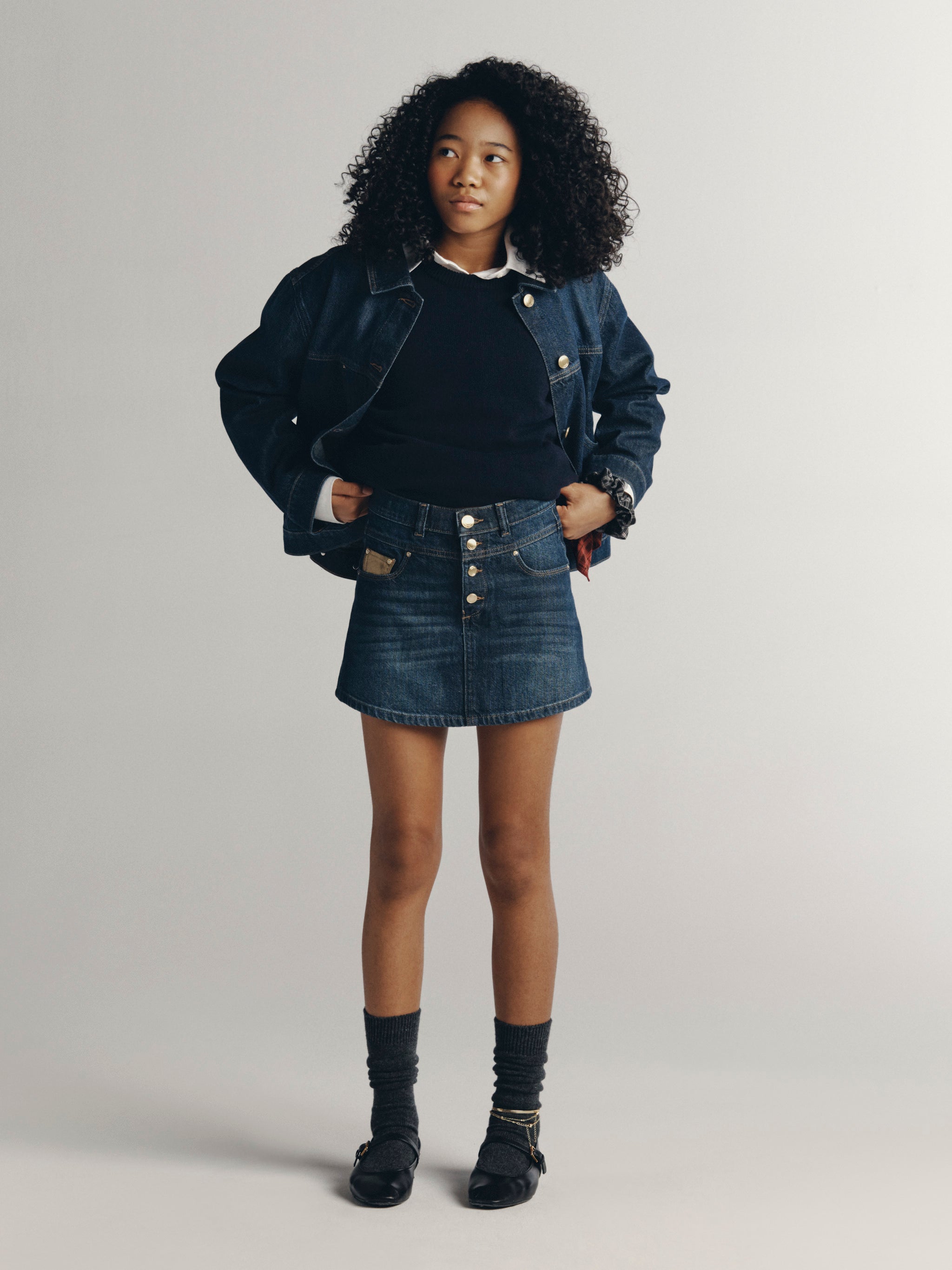 DL1961 Kids girls' Jordyn trucker jacket in Deep Water with a matching Jenny denim skirt and navy sweater, full-length front, studio.