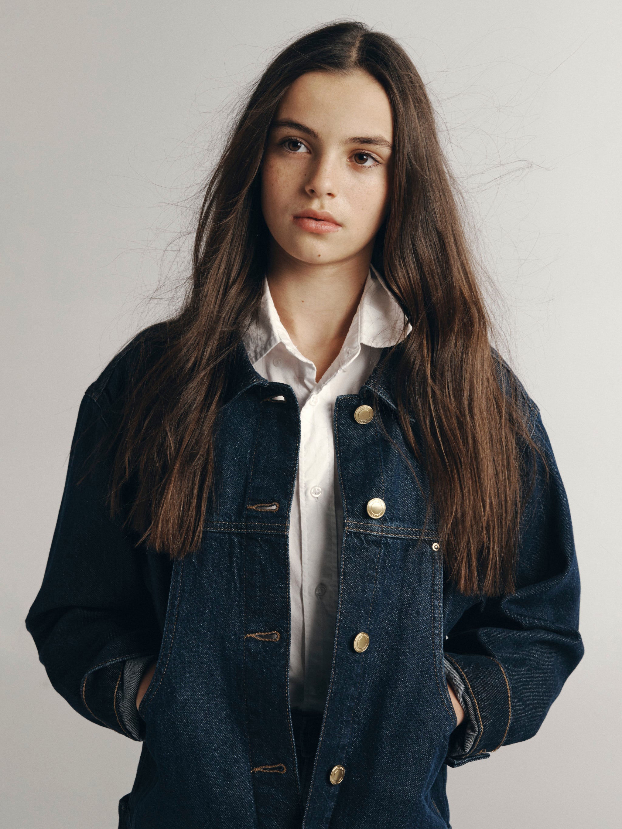 DL1961 Kids girls' Lily wide-leg jeans in Sky Fade with a denim jacket over a white shirt, waist-up portrait in a studio.