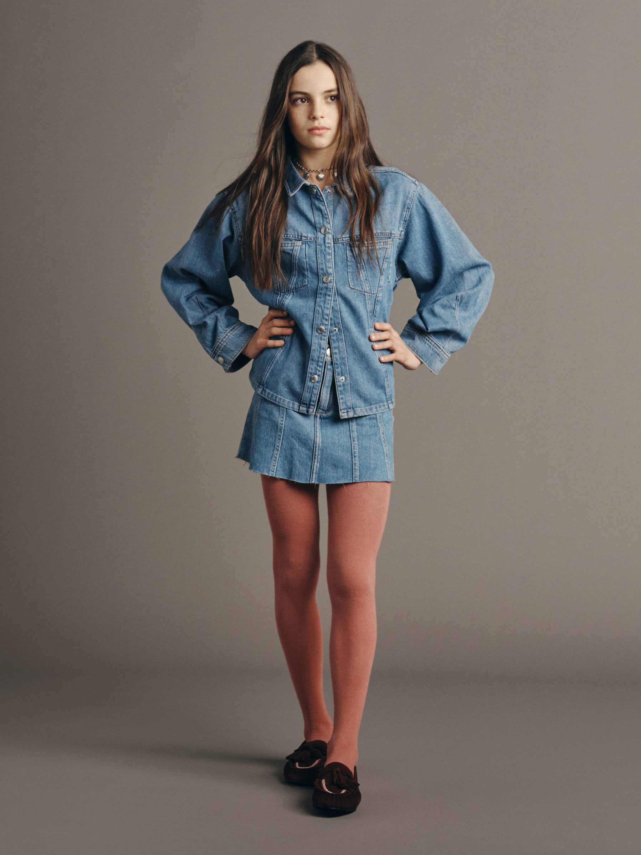 DL1961 Kids girls' Jenny denim skirt with a matching Simona top in Indigo Rose and pink tights, full-length front, studio.