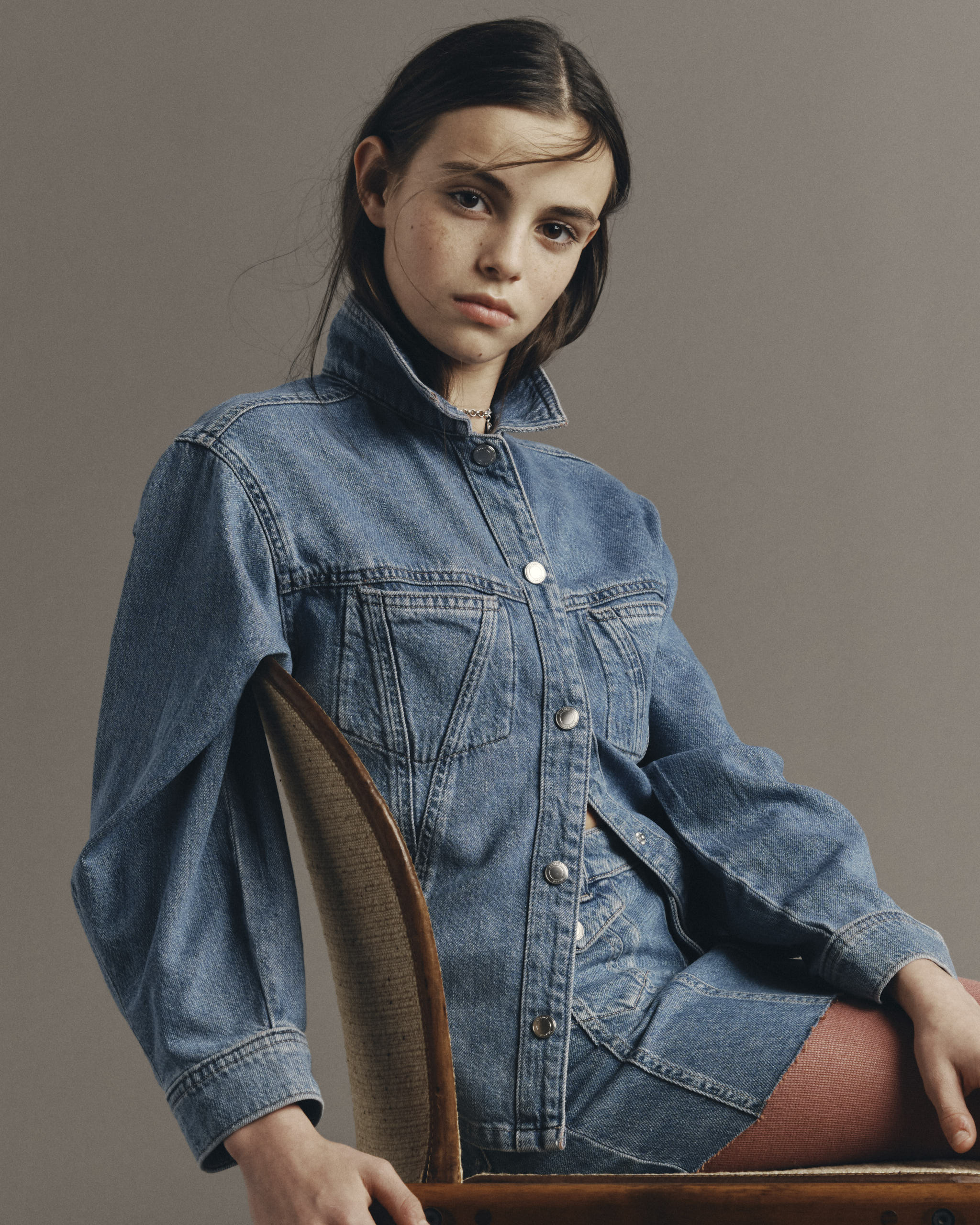 DL1961 Kids girls' Jenny denim skirt with a Simona top in Indigo Rose, seated three-quarter view in a studio.