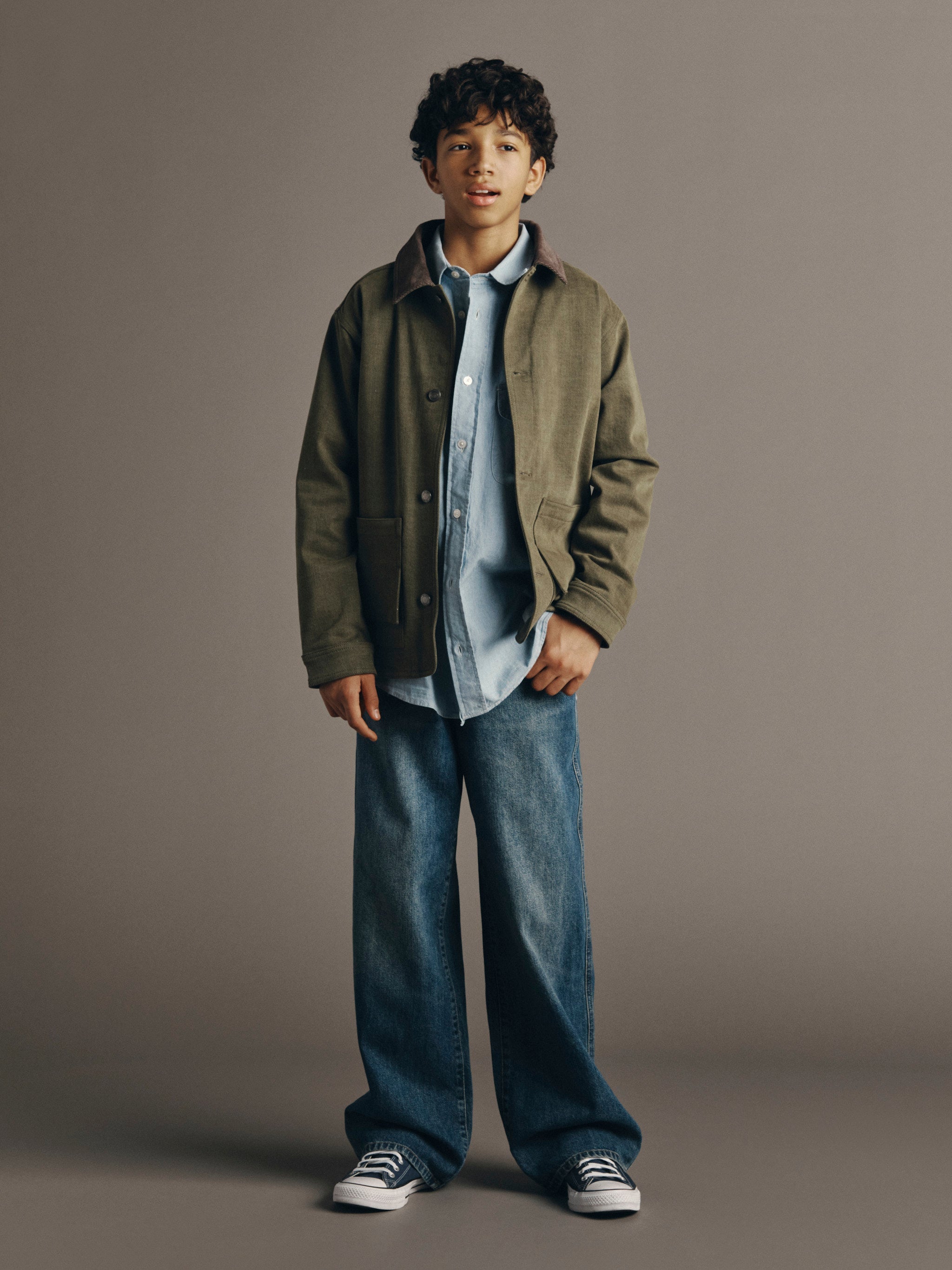 DL1961 Kids boys' Mason wide-leg jeans in Tinted Dark with an olive Loui chore jacket and blue shirt, full-length front, studio.