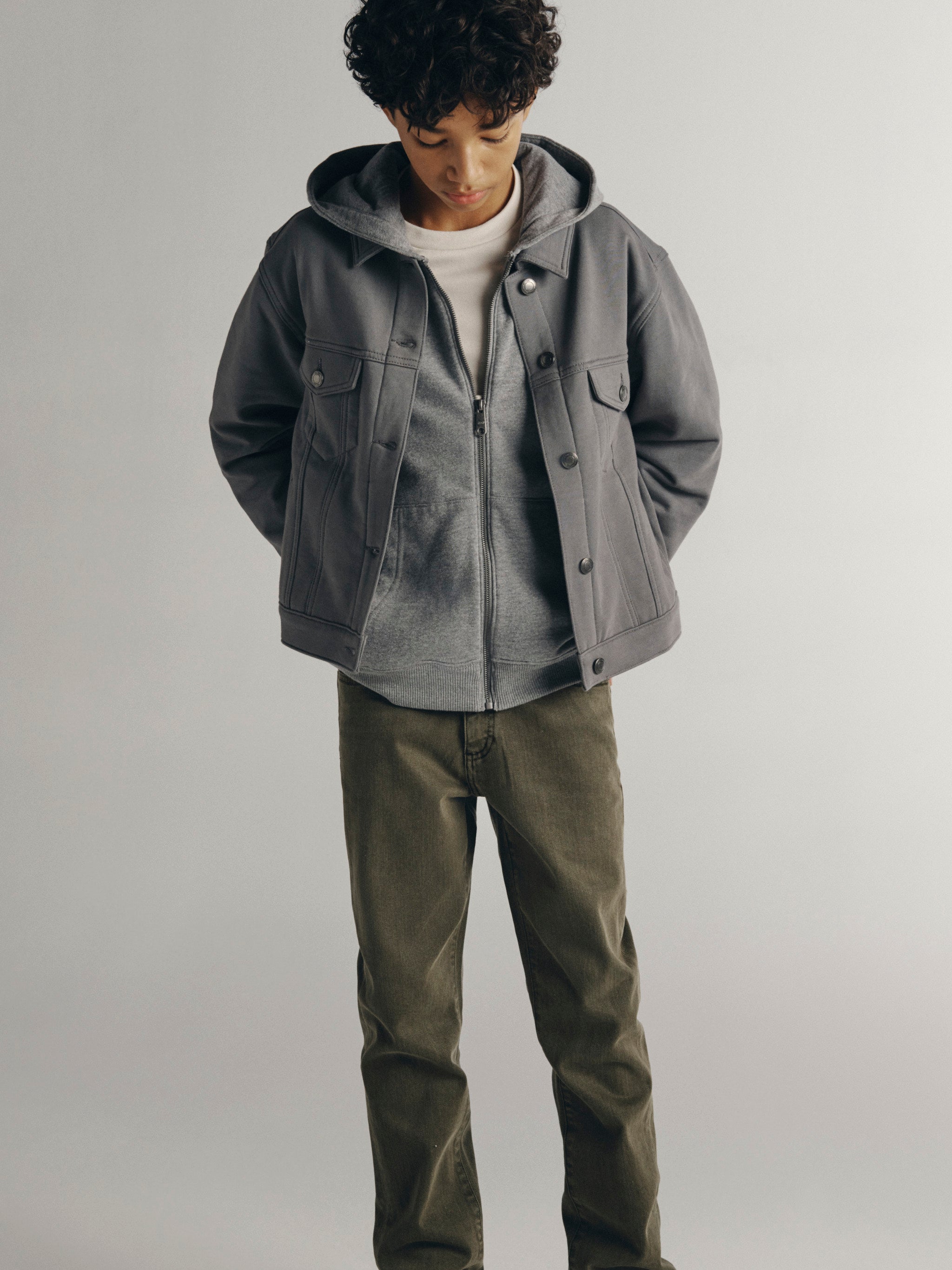 DL1961 Kids boys' Brady slim jeans in Outpost with a grey Jordyn hooded trucker jacket, full-length front view in a studio.