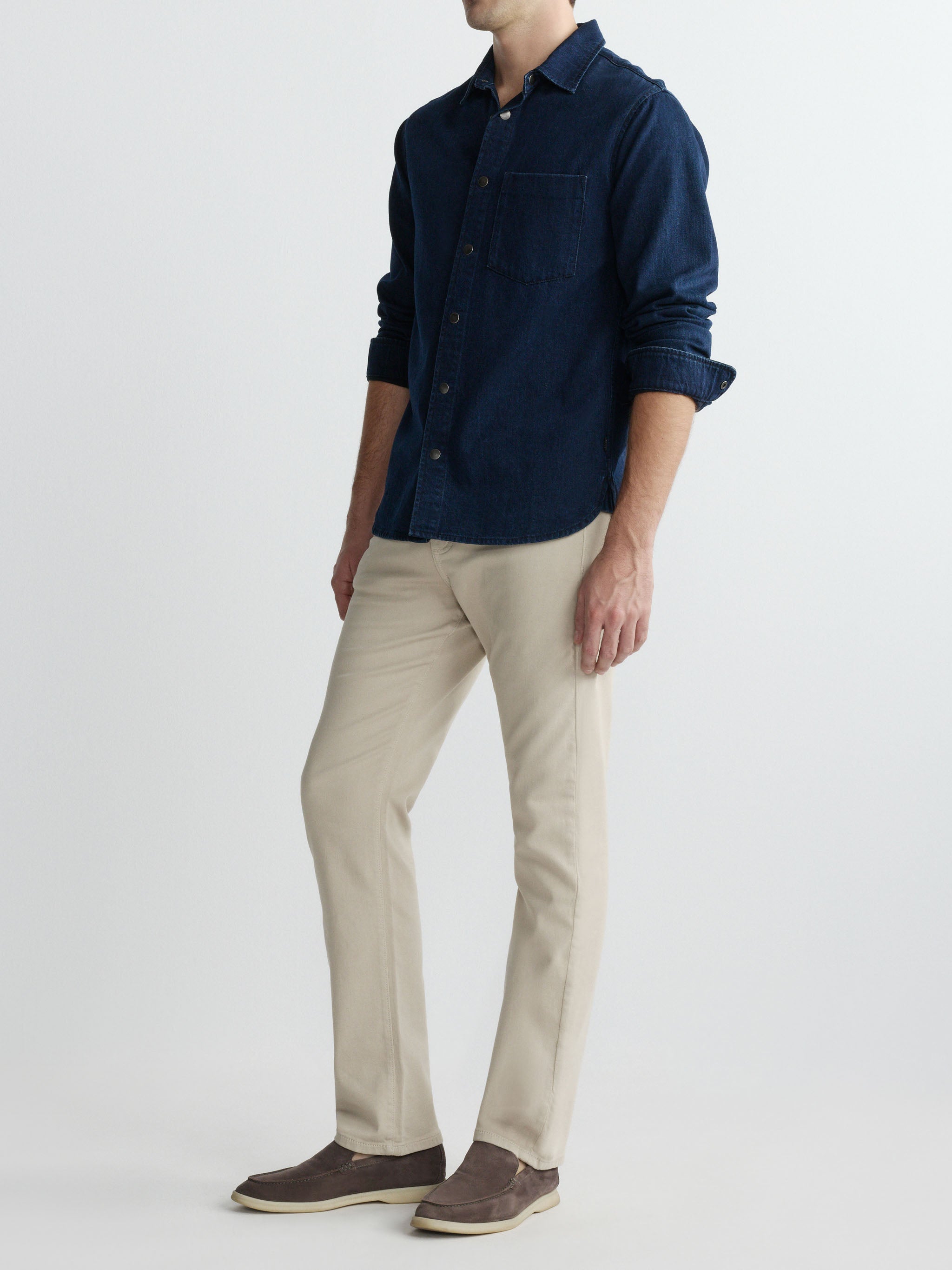 Person wearing a navy shirt and beige pants on a white background