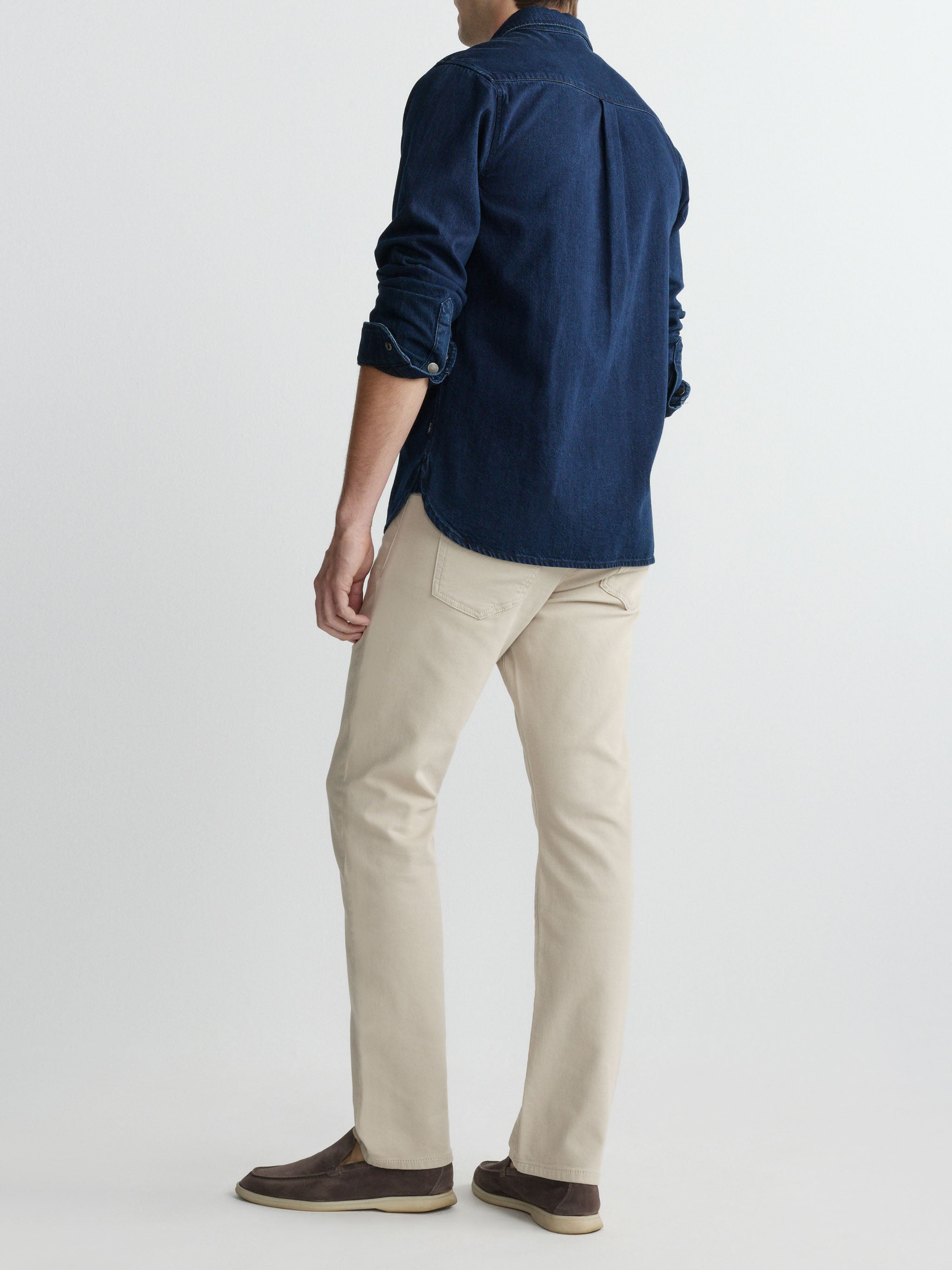 Person wearing a navy shirt and beige pants on a white background