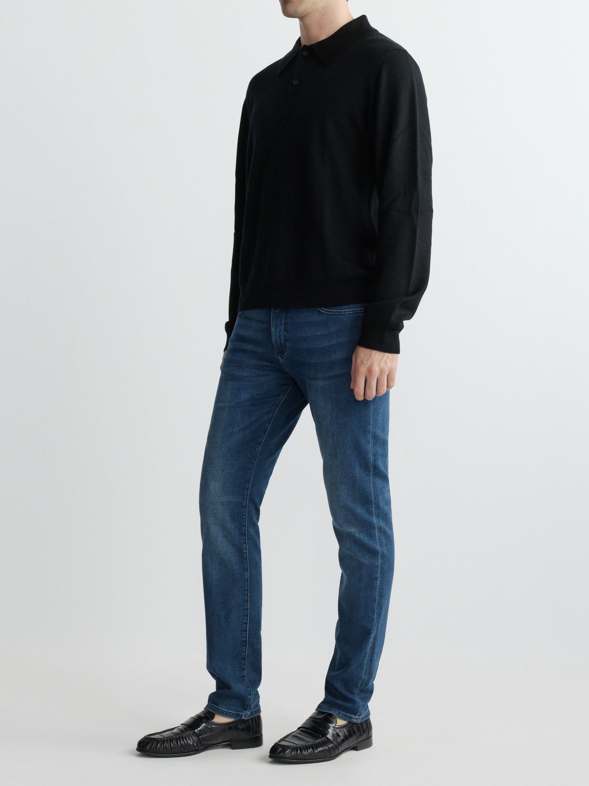 Person wearing a black sweater and blue jeans on a white background