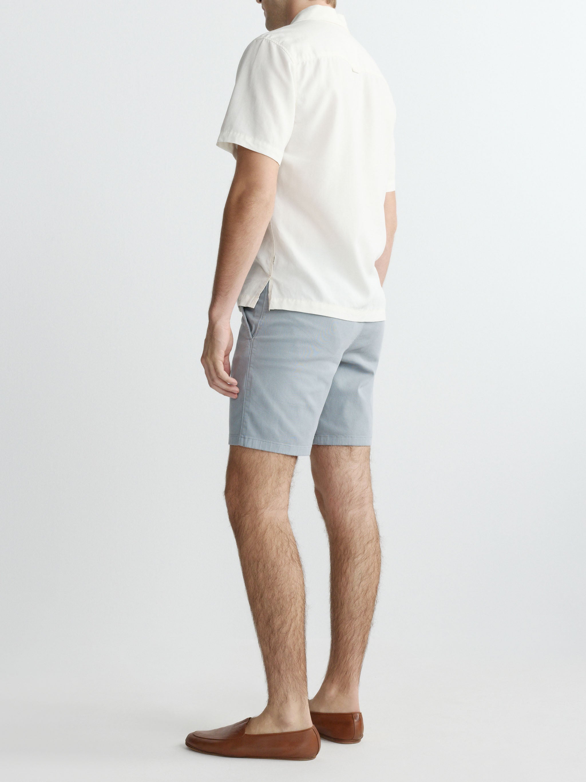 Man wearing a white shirt and light blue shorts on a plain background