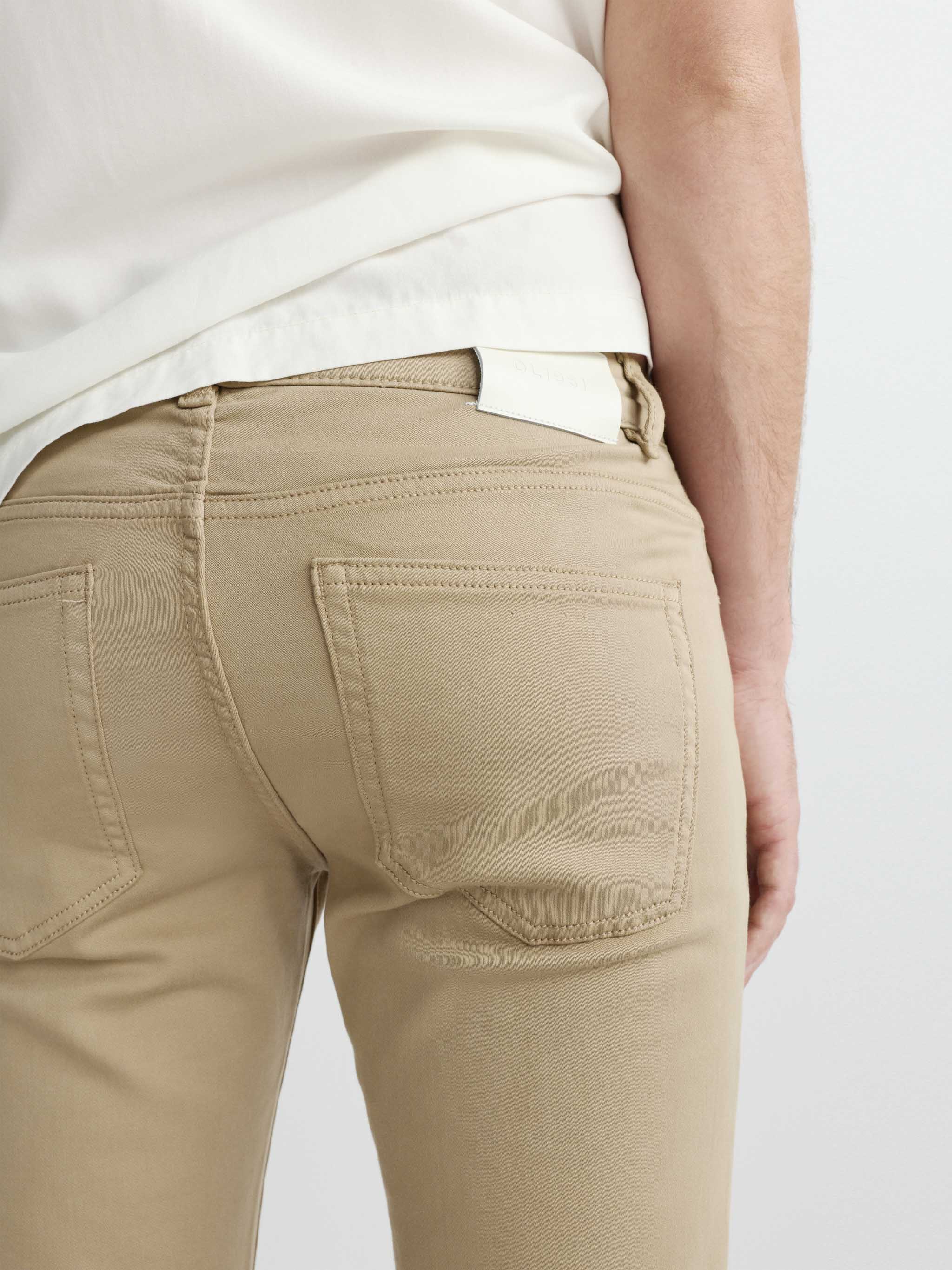 Beige pants worn by a person on a white background