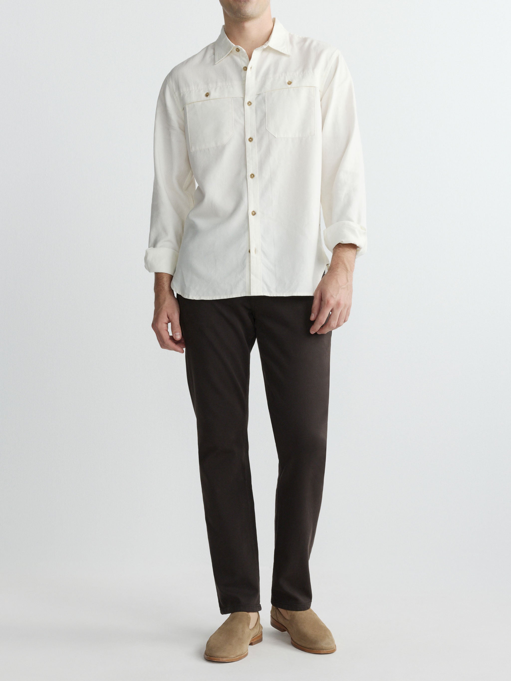 Person wearing a white button-up shirt and black pants on a plain background