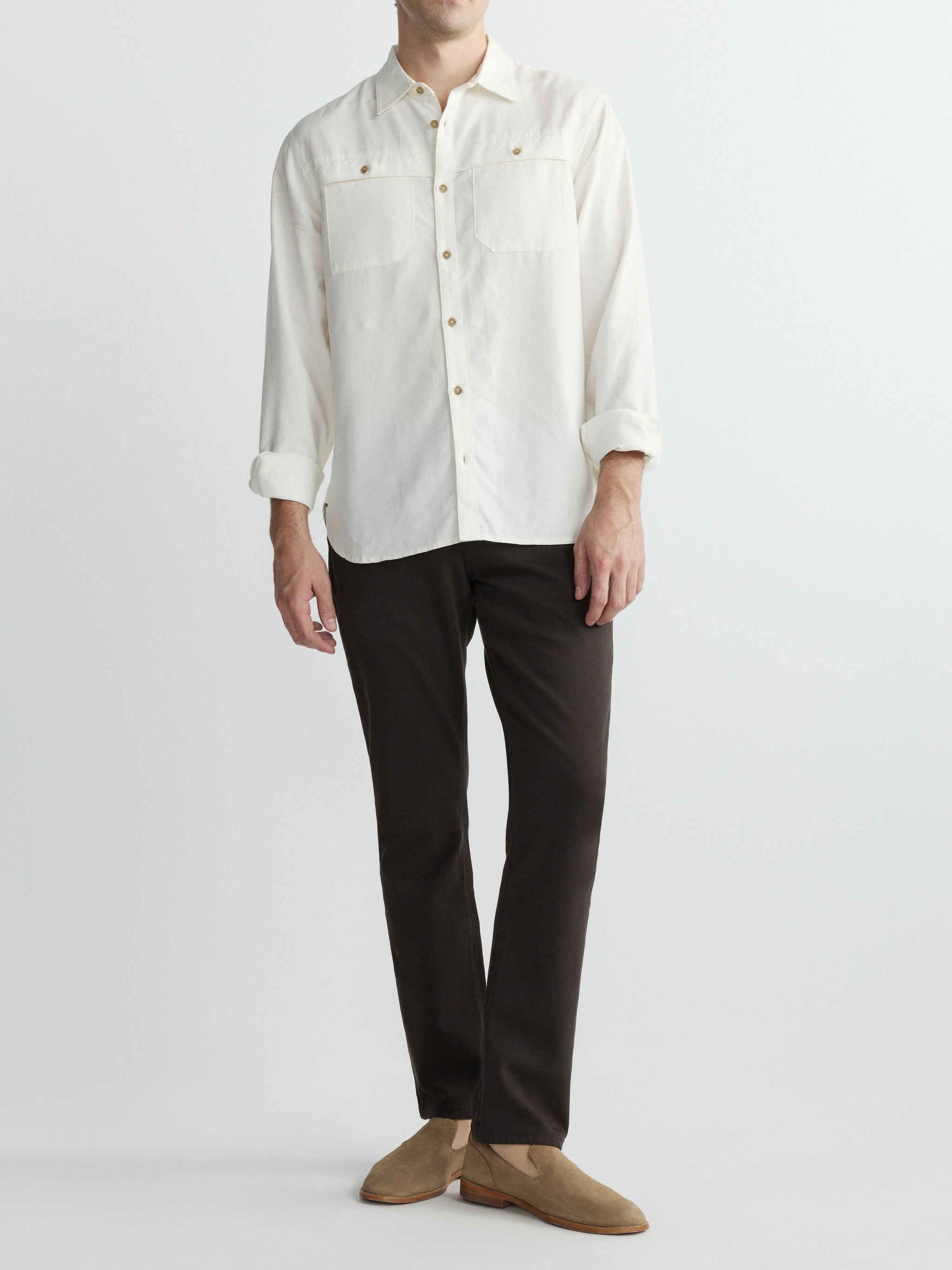 Person wearing a white button-up shirt and black pants on a light gray background
