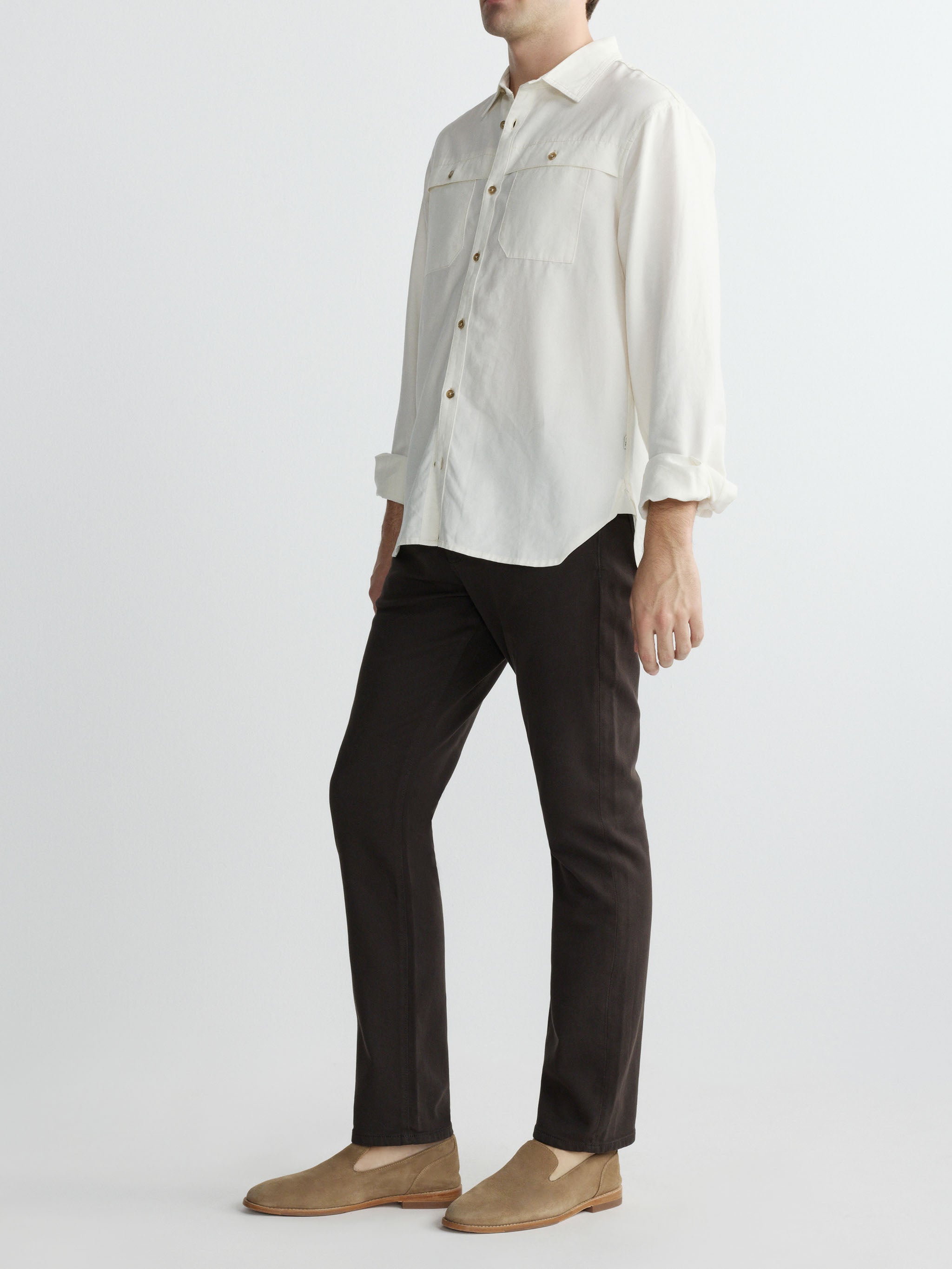 Person wearing a light gray shirt and dark pants on a white background