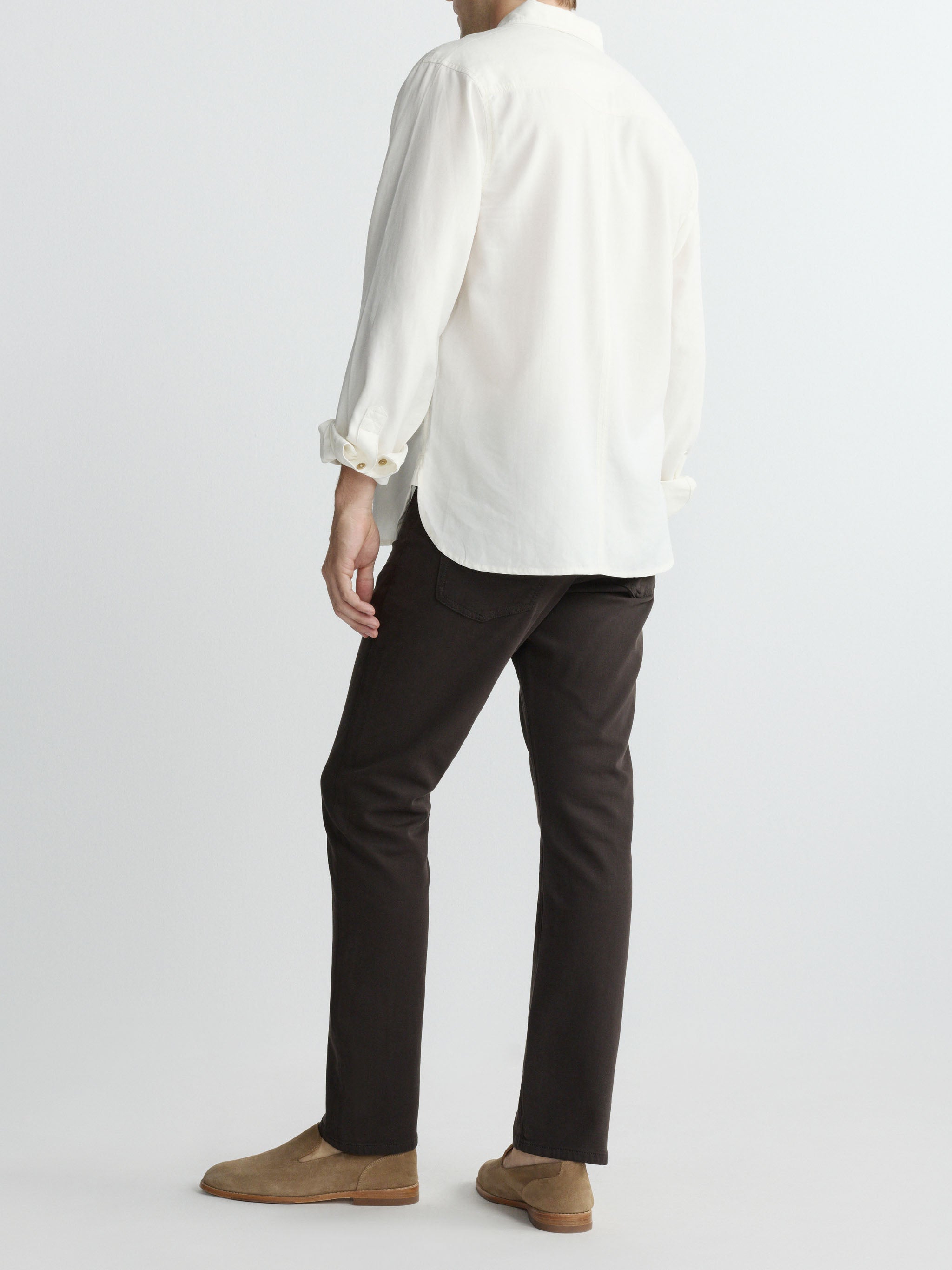 Person wearing a white shirt and black pants on a plain background