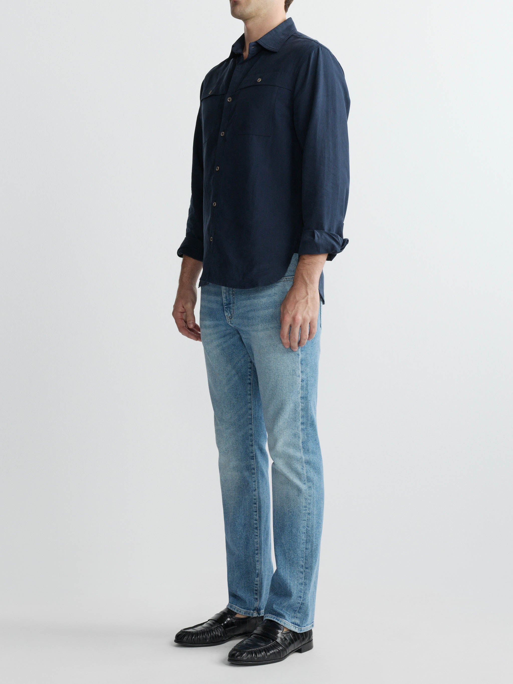 Person wearing a navy shirt and light blue jeans on a white background