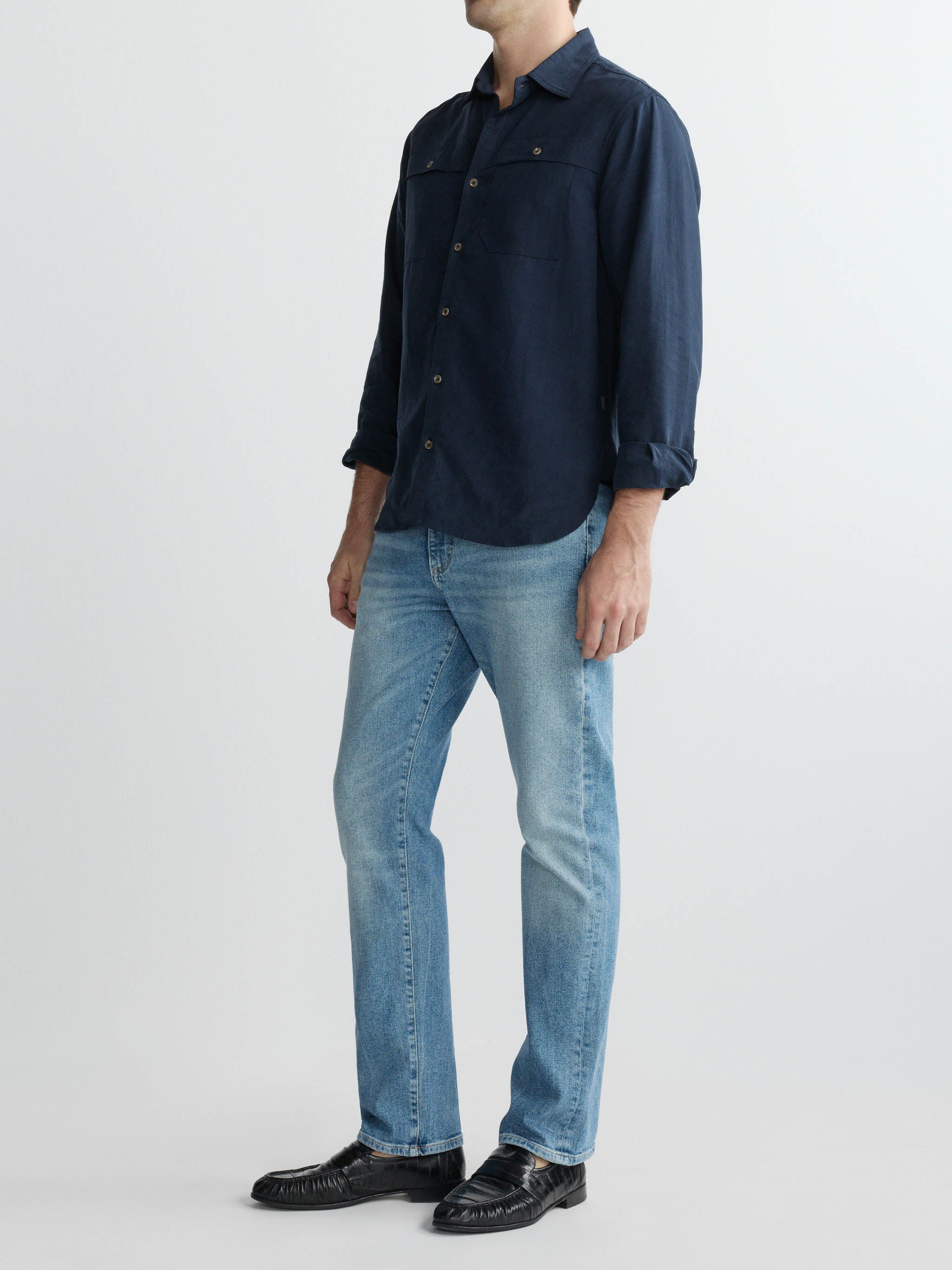 Person wearing a dark blue shirt and light blue jeans on a white background