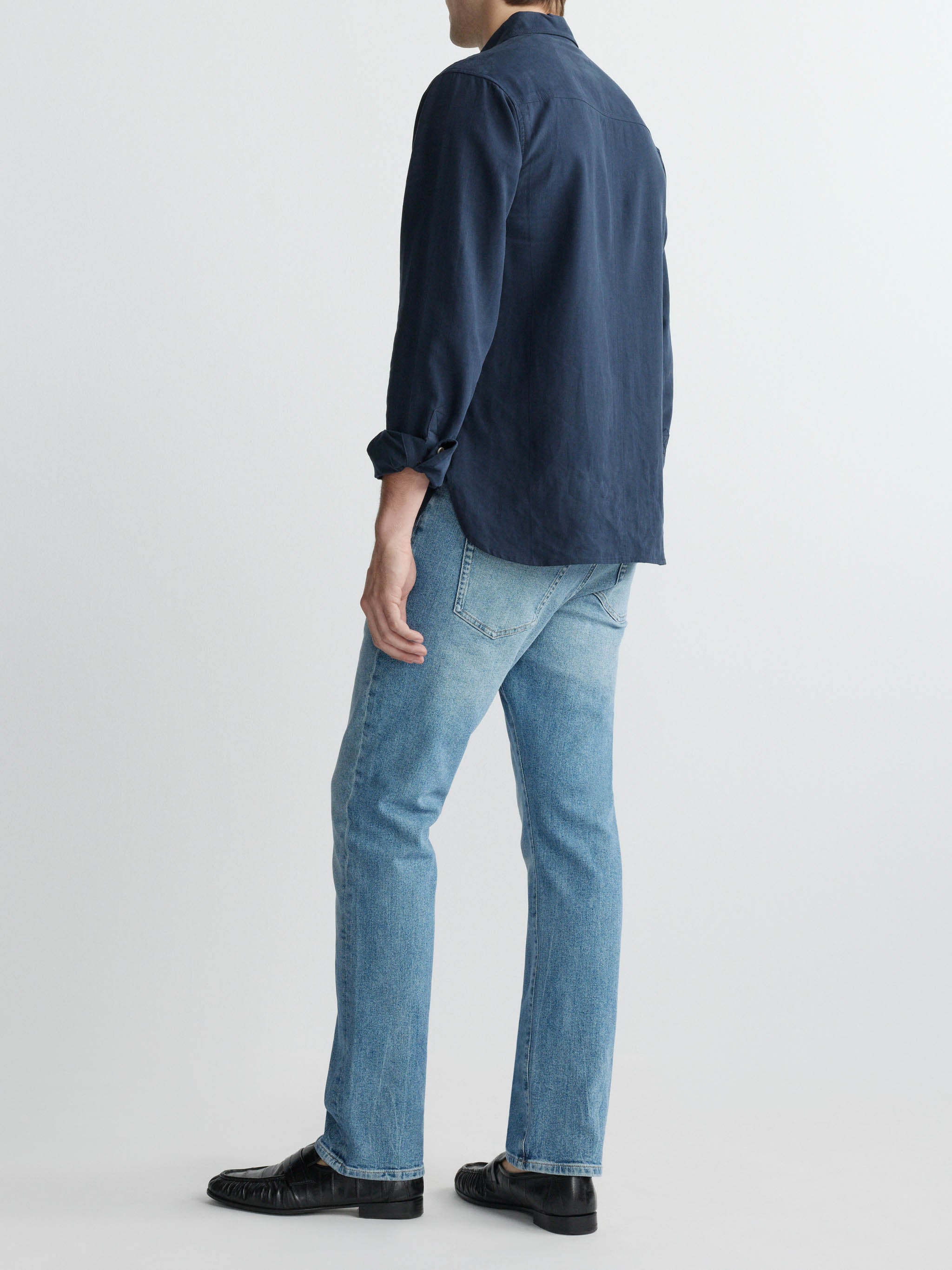 Person wearing a navy shirt and light blue jeans on a white background