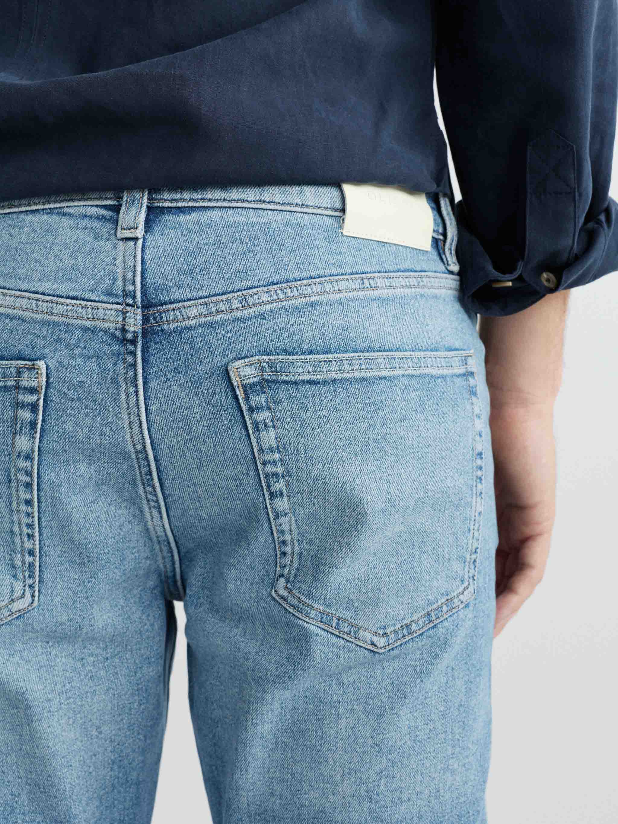 Person wearing light blue jeans with a plain background