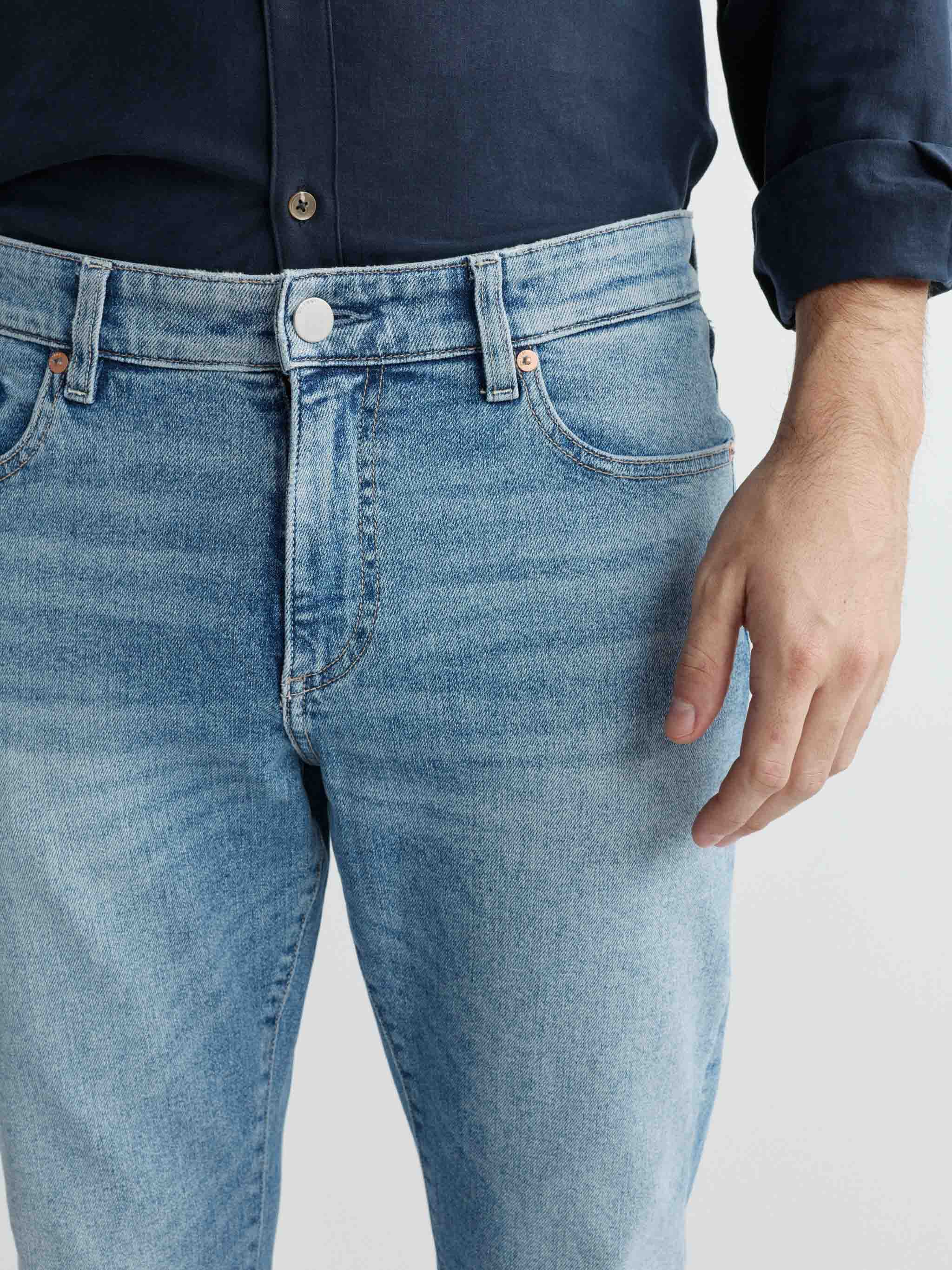 Person wearing light blue jeans with a plain background