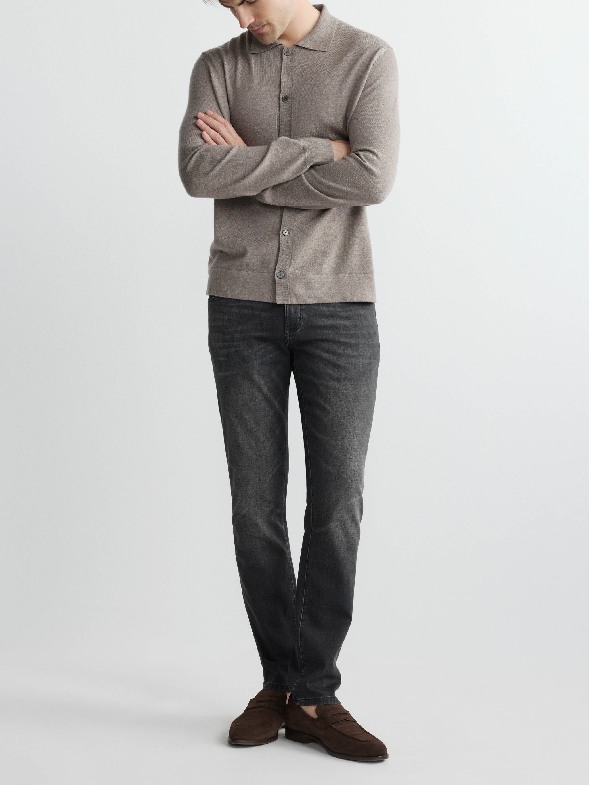 Person wearing a gray sweater and dark jeans on a white background