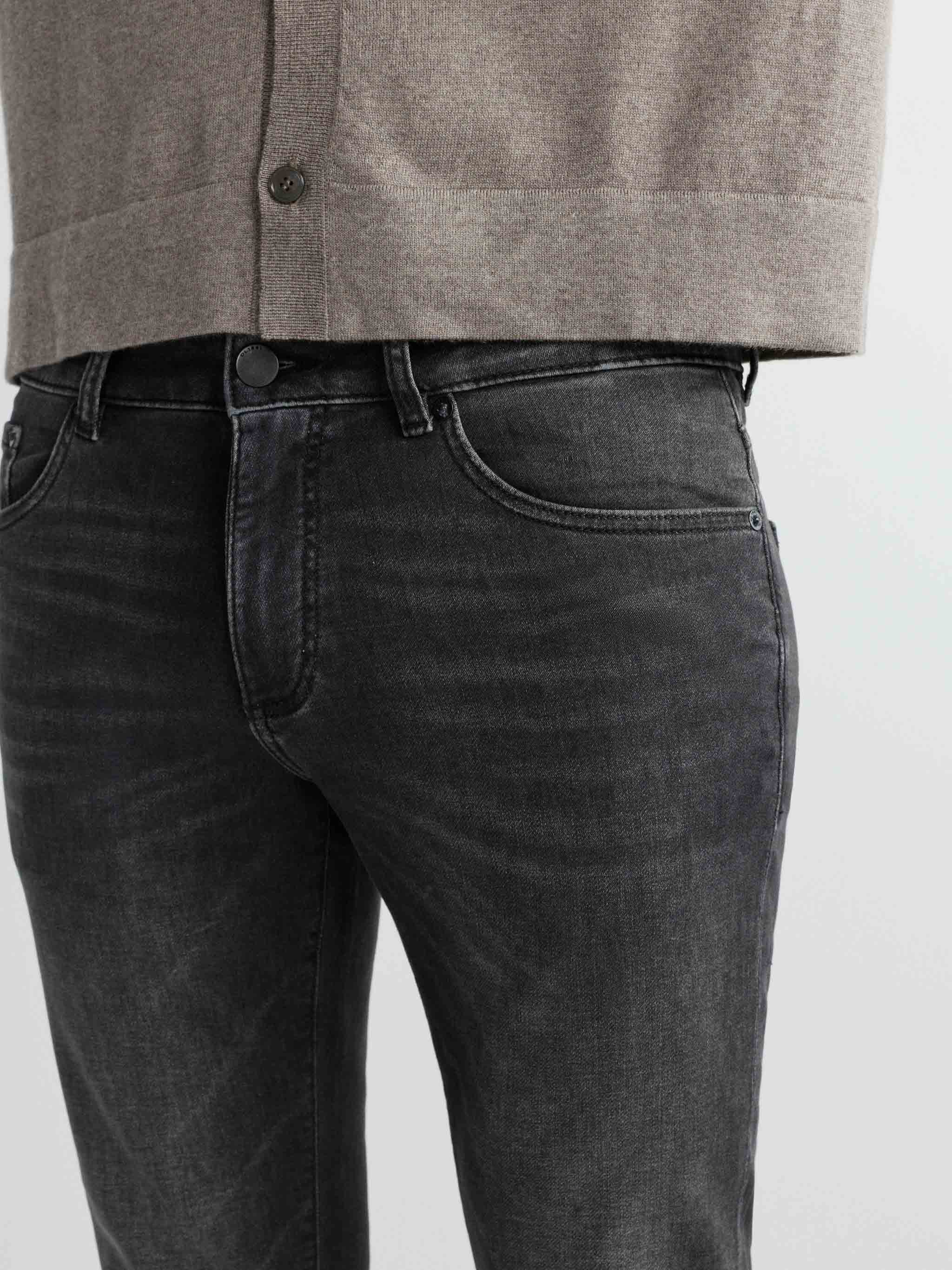 Person wearing a gray shirt and black jeans on a light gray background