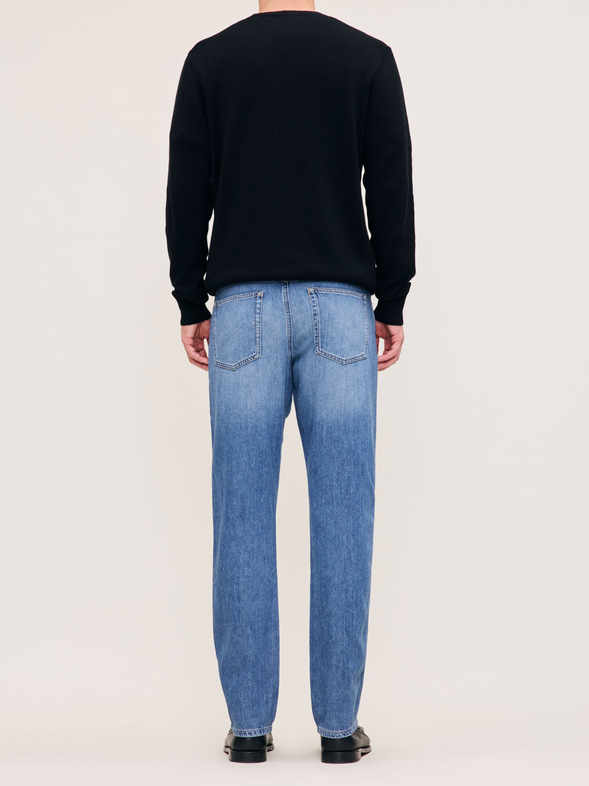 DL1961 men's Classic Crewneck sweater in black, back view on model with blue jeans.