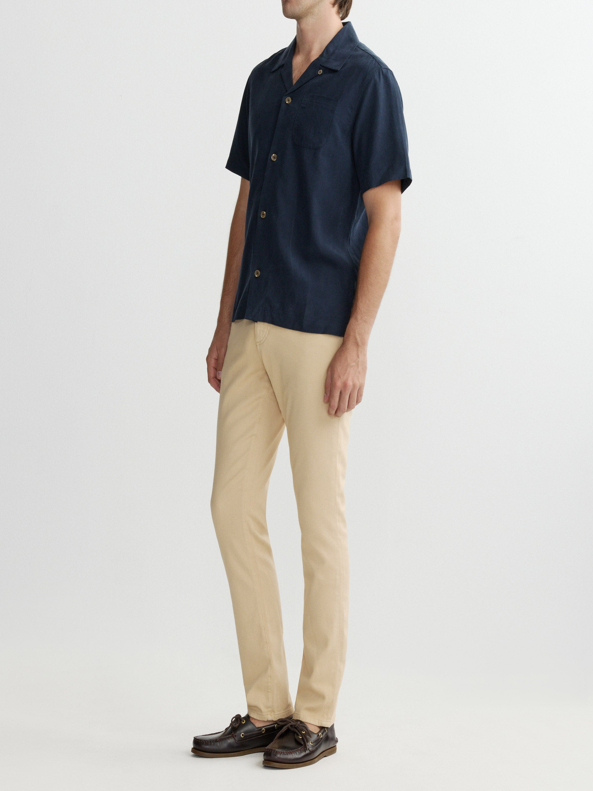 Person wearing a navy short-sleeve shirt and beige pants on a white background