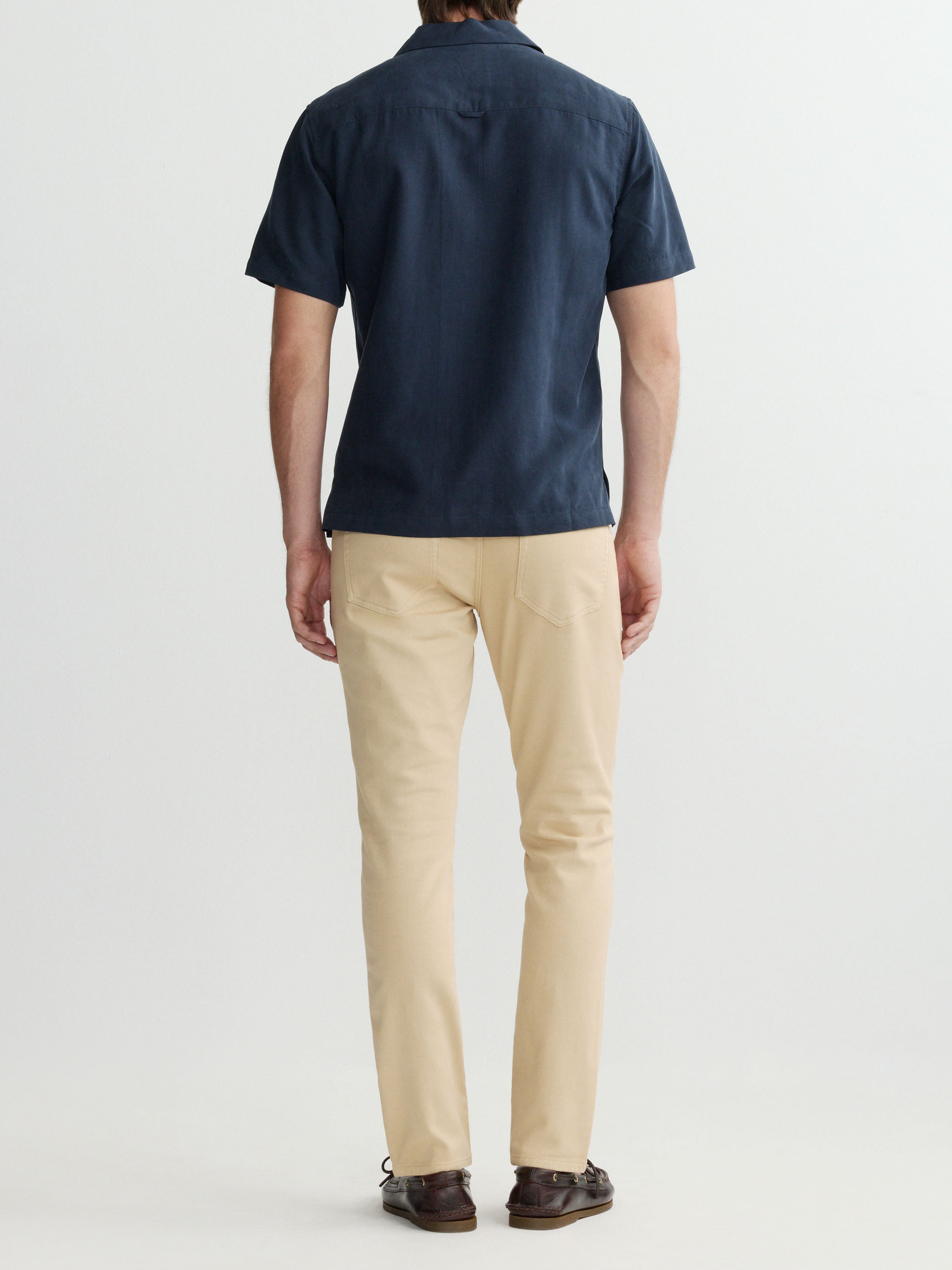Person wearing a navy polo shirt and beige pants on a white background