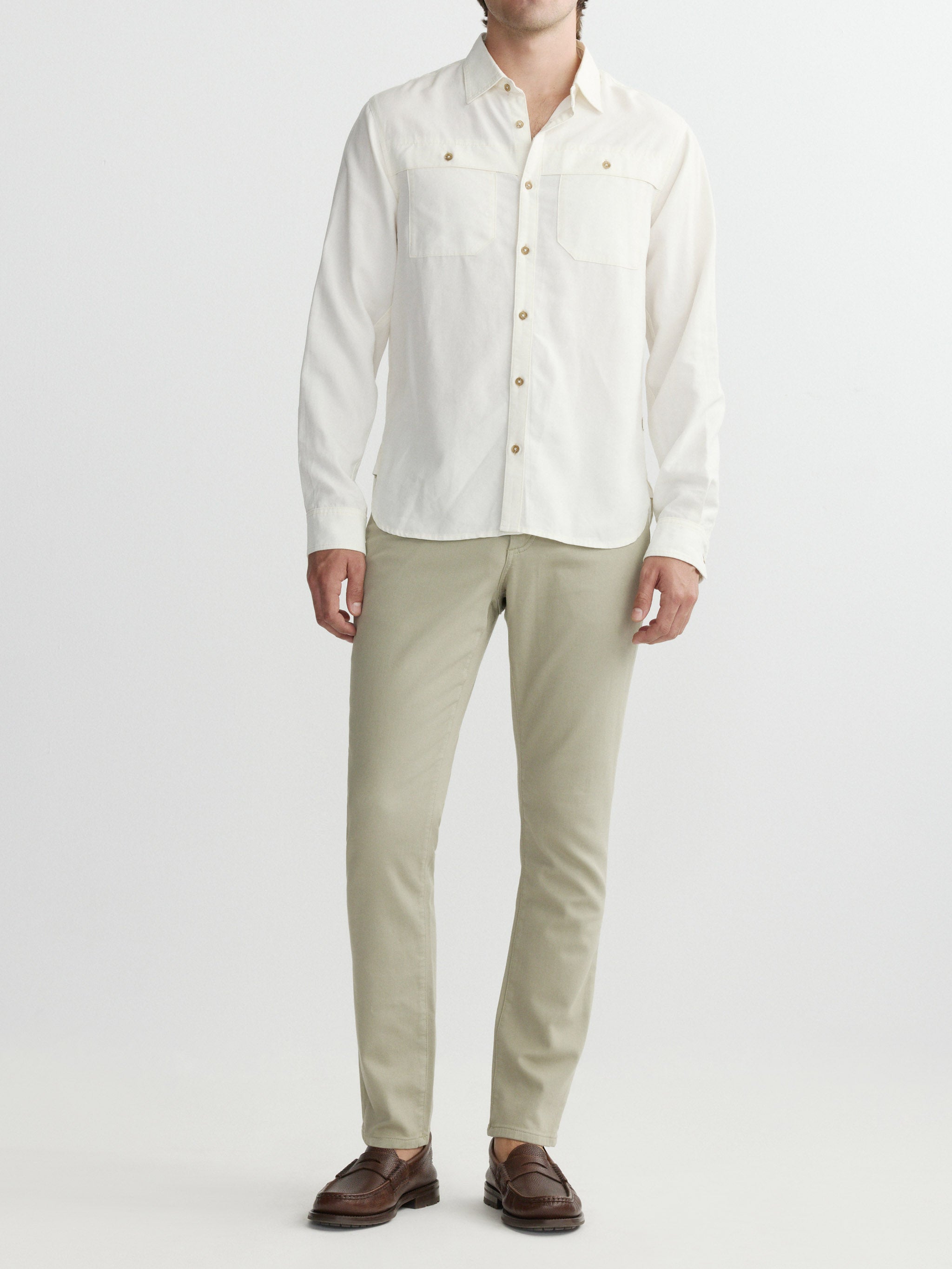Person wearing a white button-up shirt and beige pants on a white background