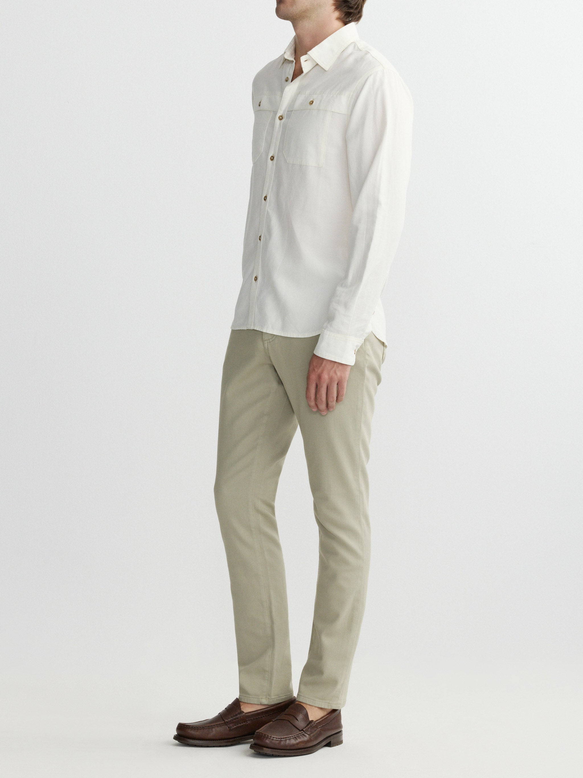 Man wearing a light-colored shirt and beige pants on a white background