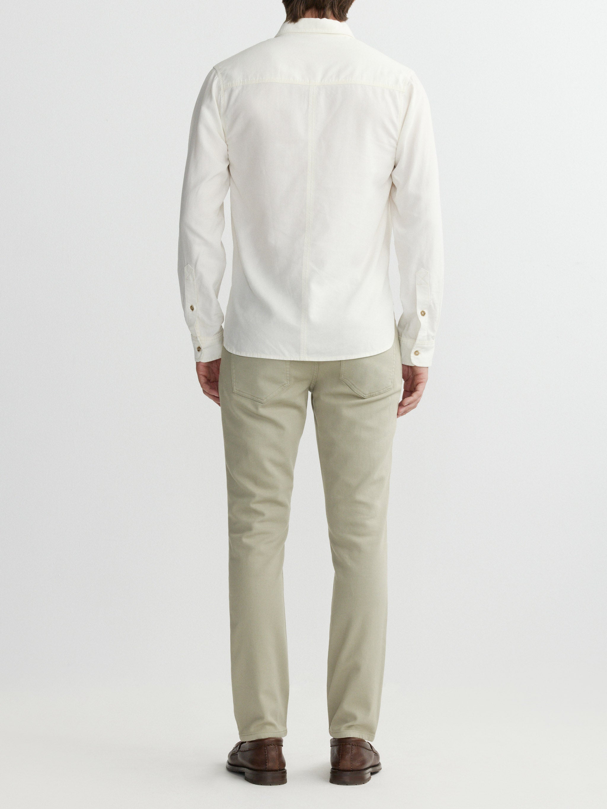 Person wearing a white jacket and beige pants on a white background