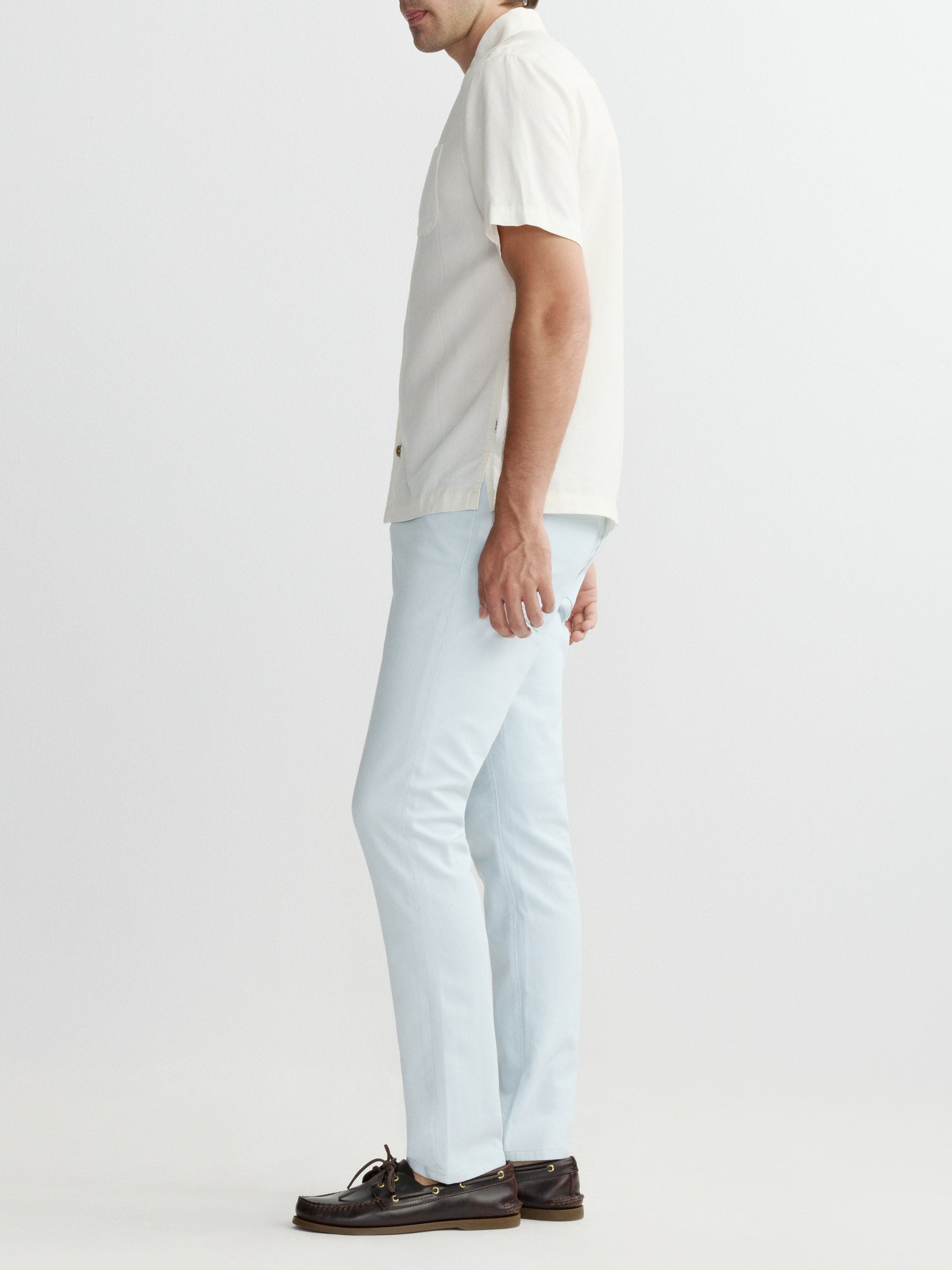 Person wearing a white shirt and light blue pants on a plain background