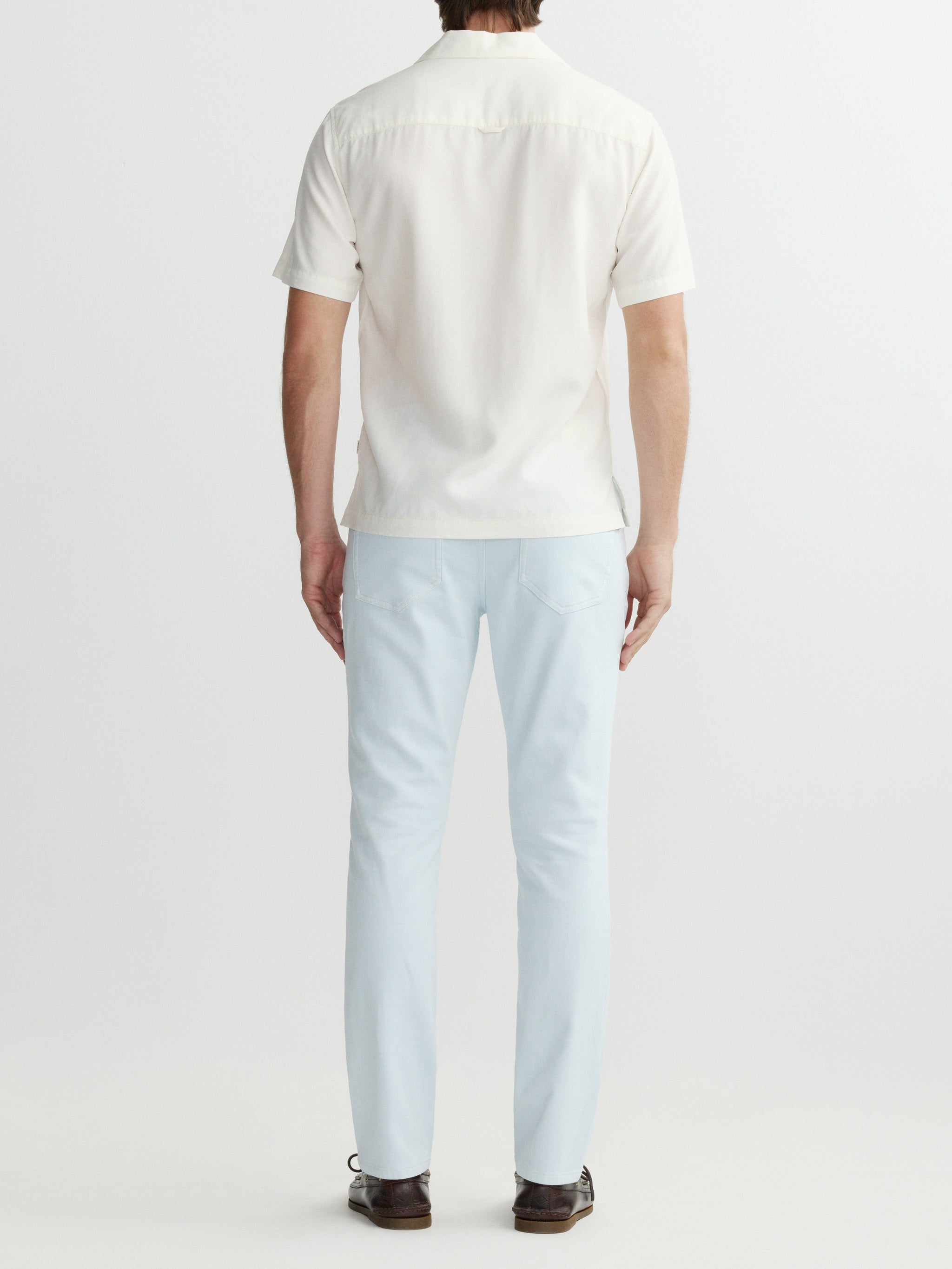 Person wearing a white shirt and light blue jeans on a plain background