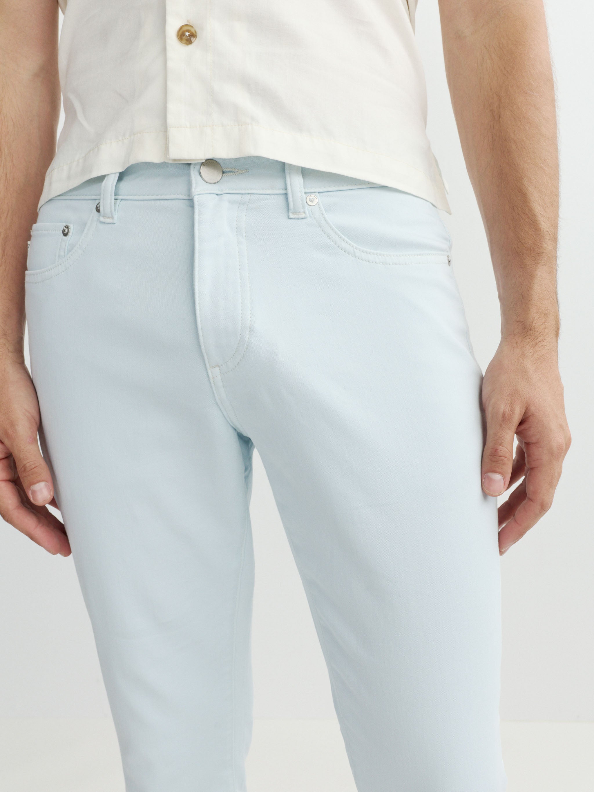 Light blue jeans worn by a person on a plain background