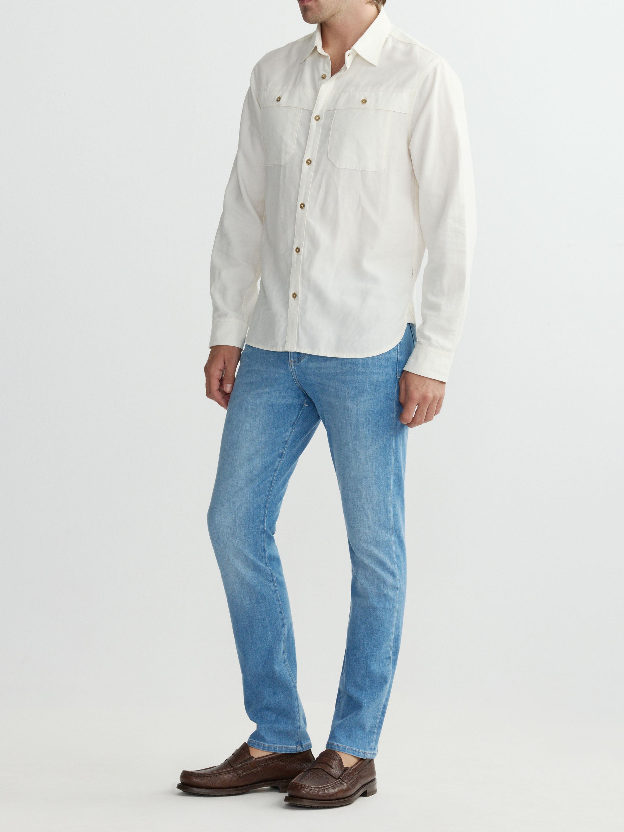 Person wearing a white button-up shirt and blue jeans on a white background
