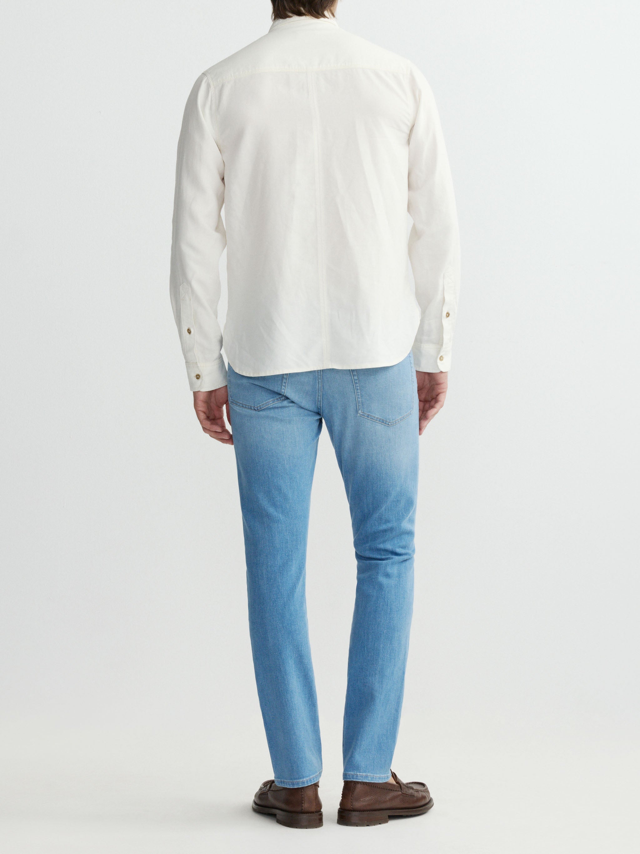 Person wearing a white shirt and light blue jeans on a plain background