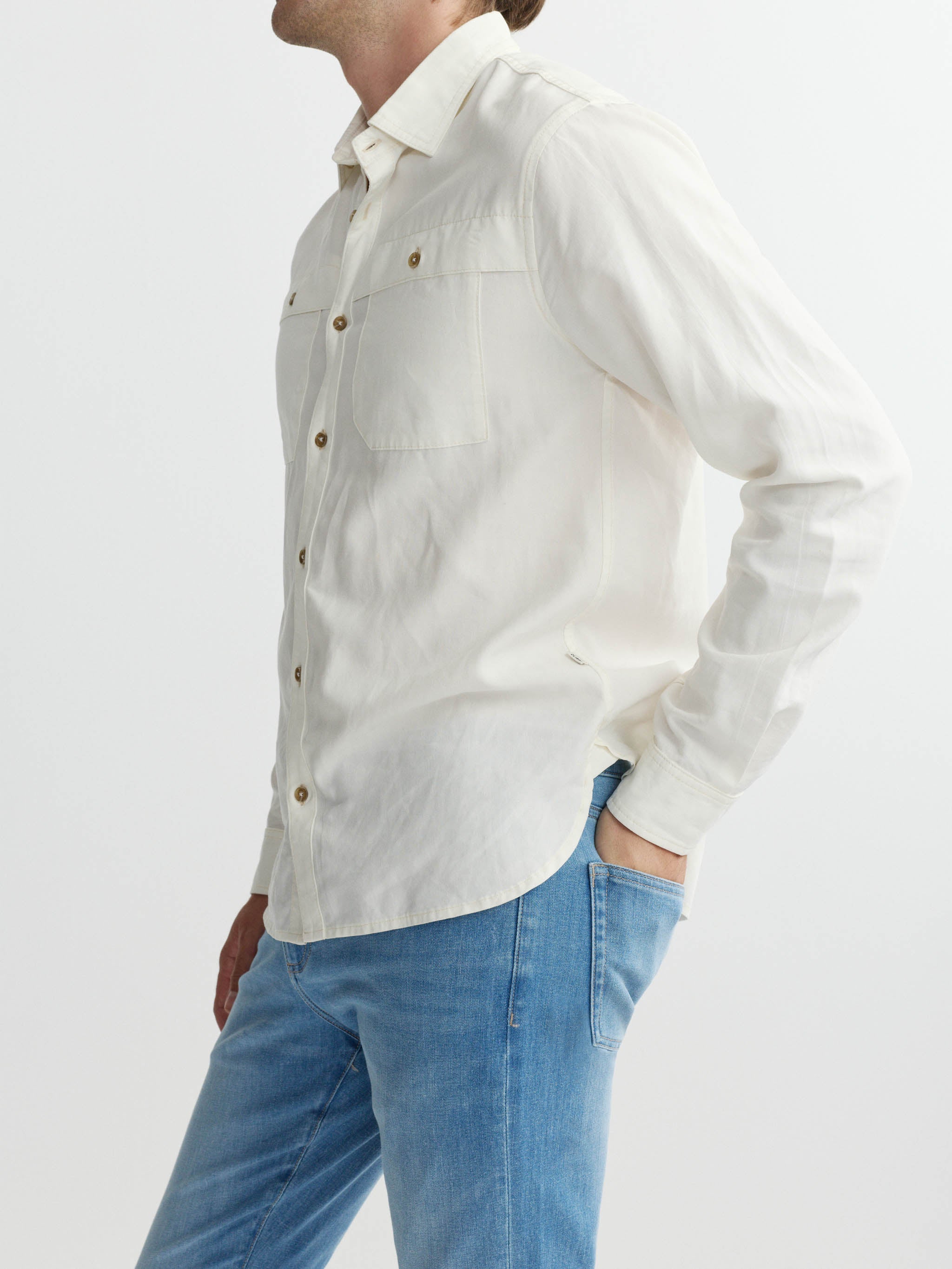 Person wearing a white shirt and blue jeans on a plain background