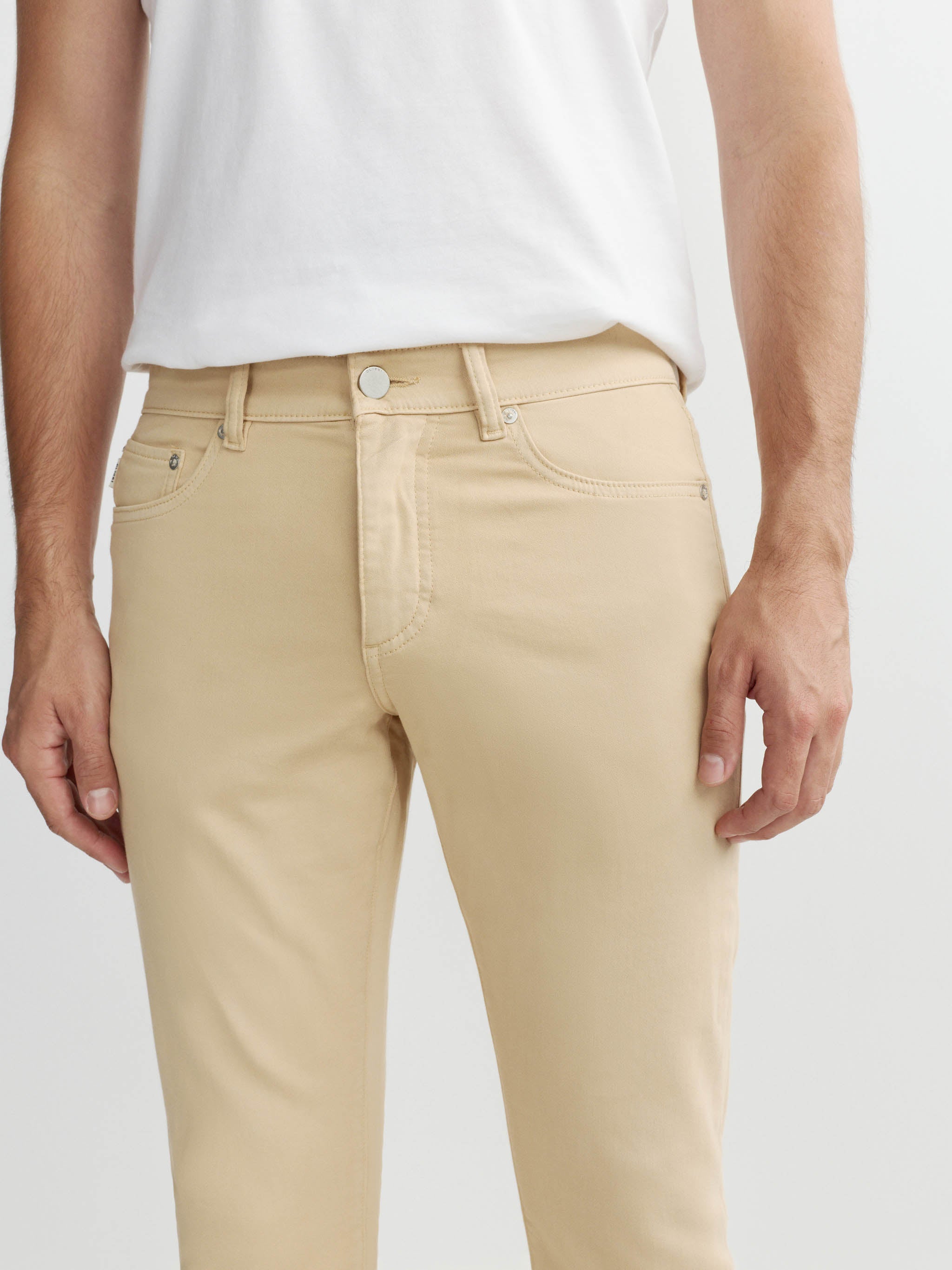 Beige pants worn by a person on a white background