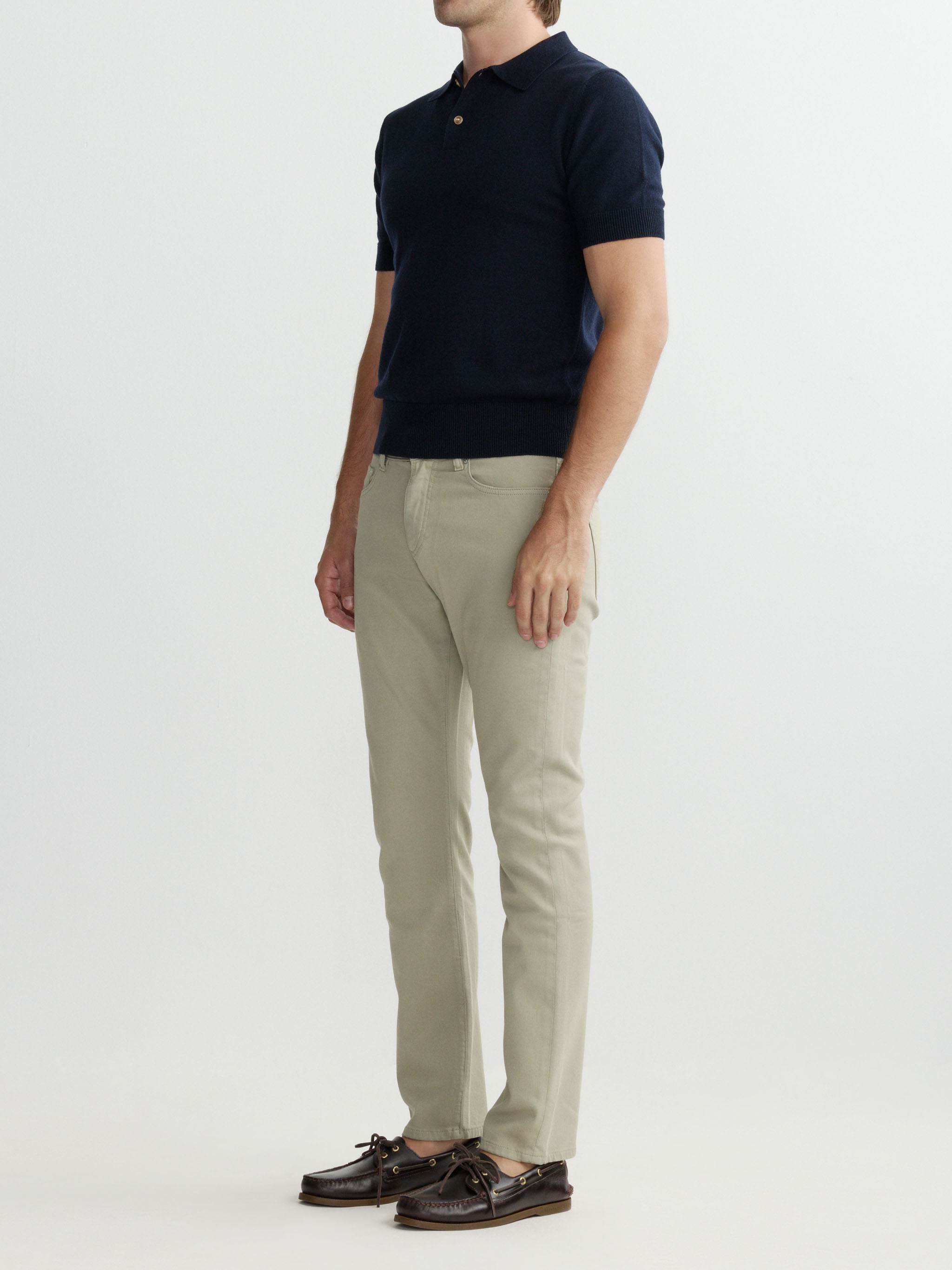 Man wearing a navy polo shirt and beige pants on a white background