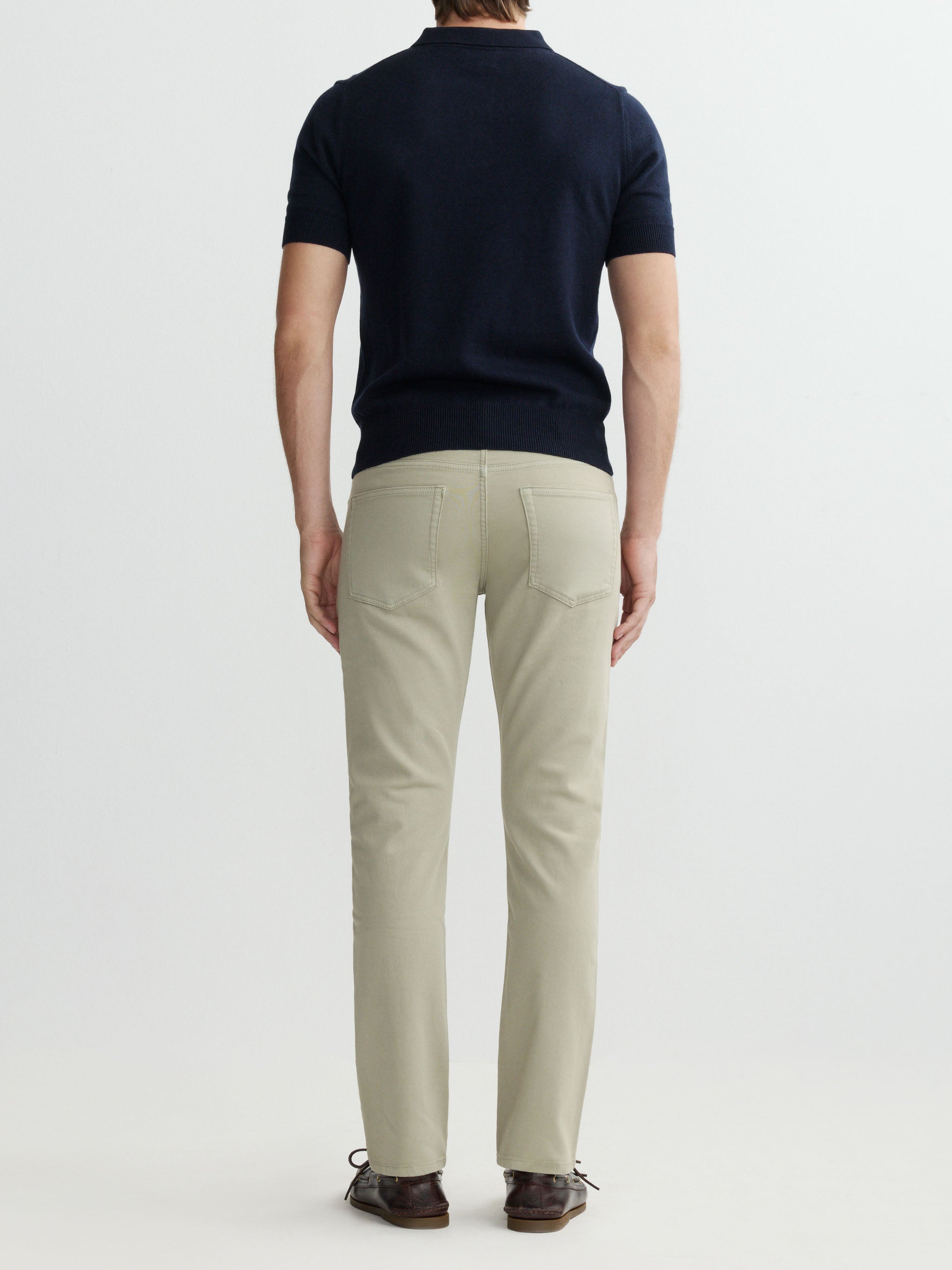 Person wearing a navy polo shirt and beige pants on a white background
