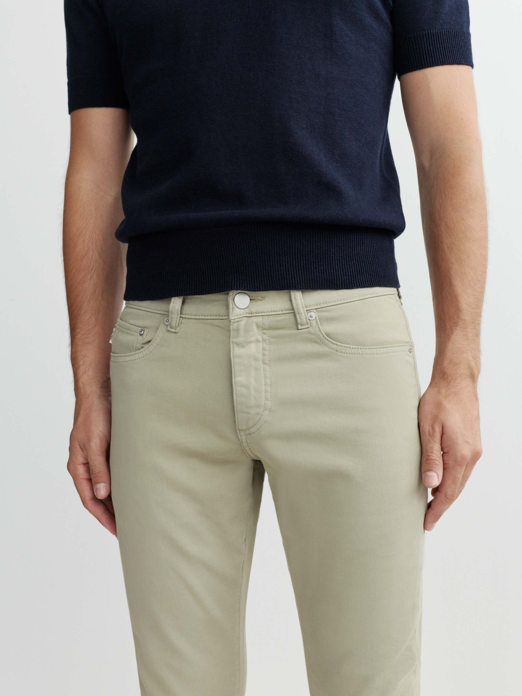 Person wearing a navy sweater and beige pants on a white background