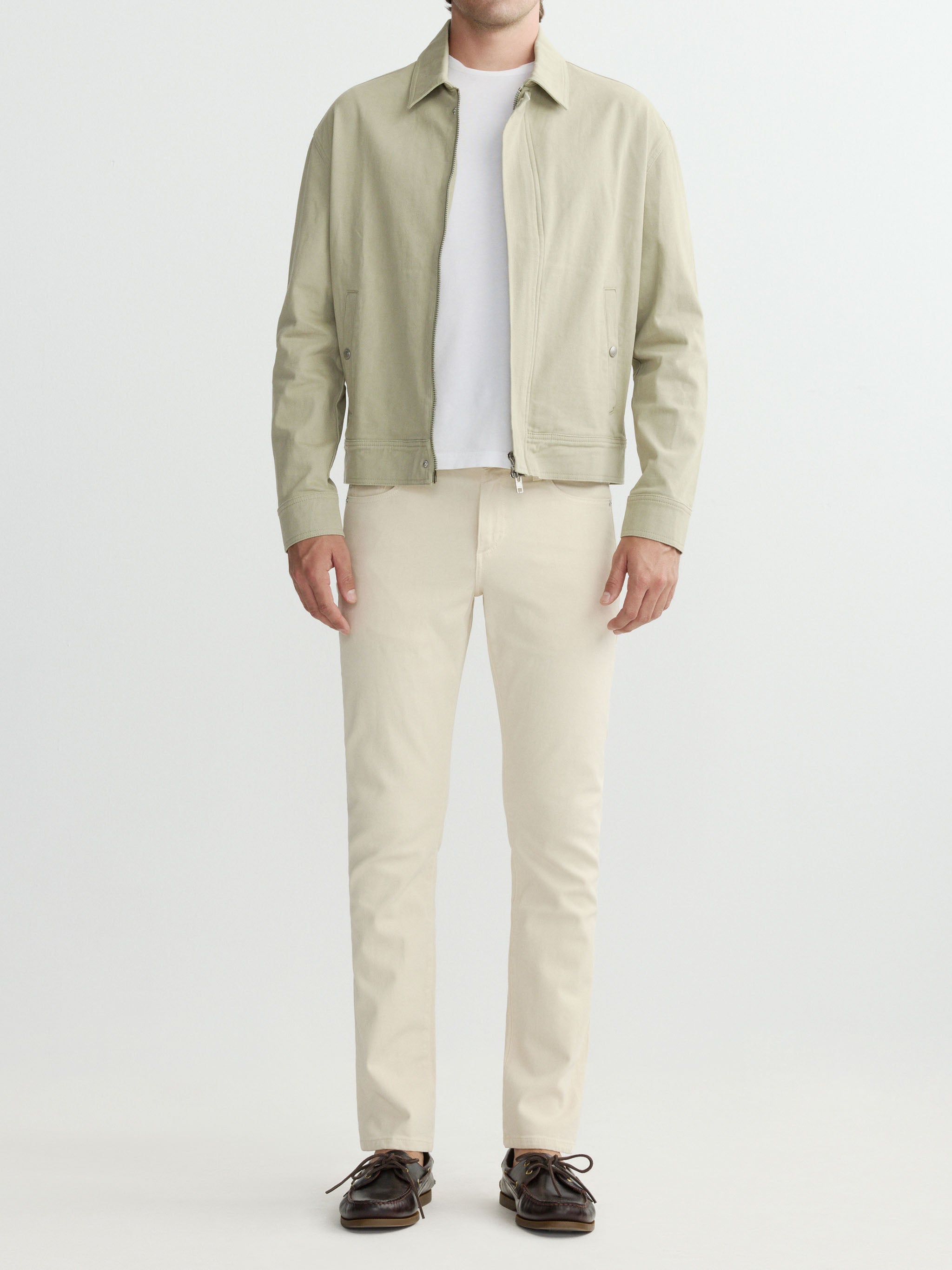 Man wearing a light green jacket, white shirt, beige pants, and brown shoes on a white background