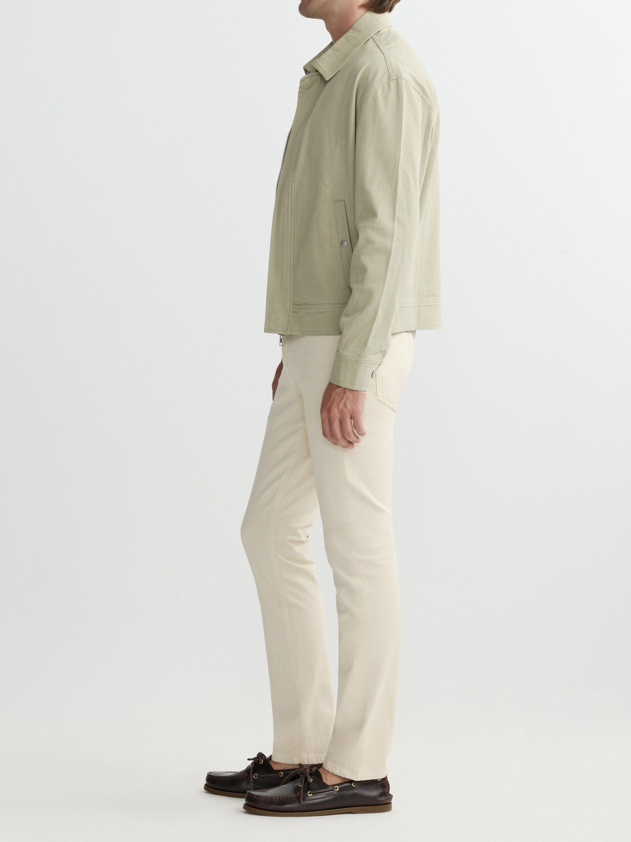 Person wearing a light green jacket and beige pants on a white background