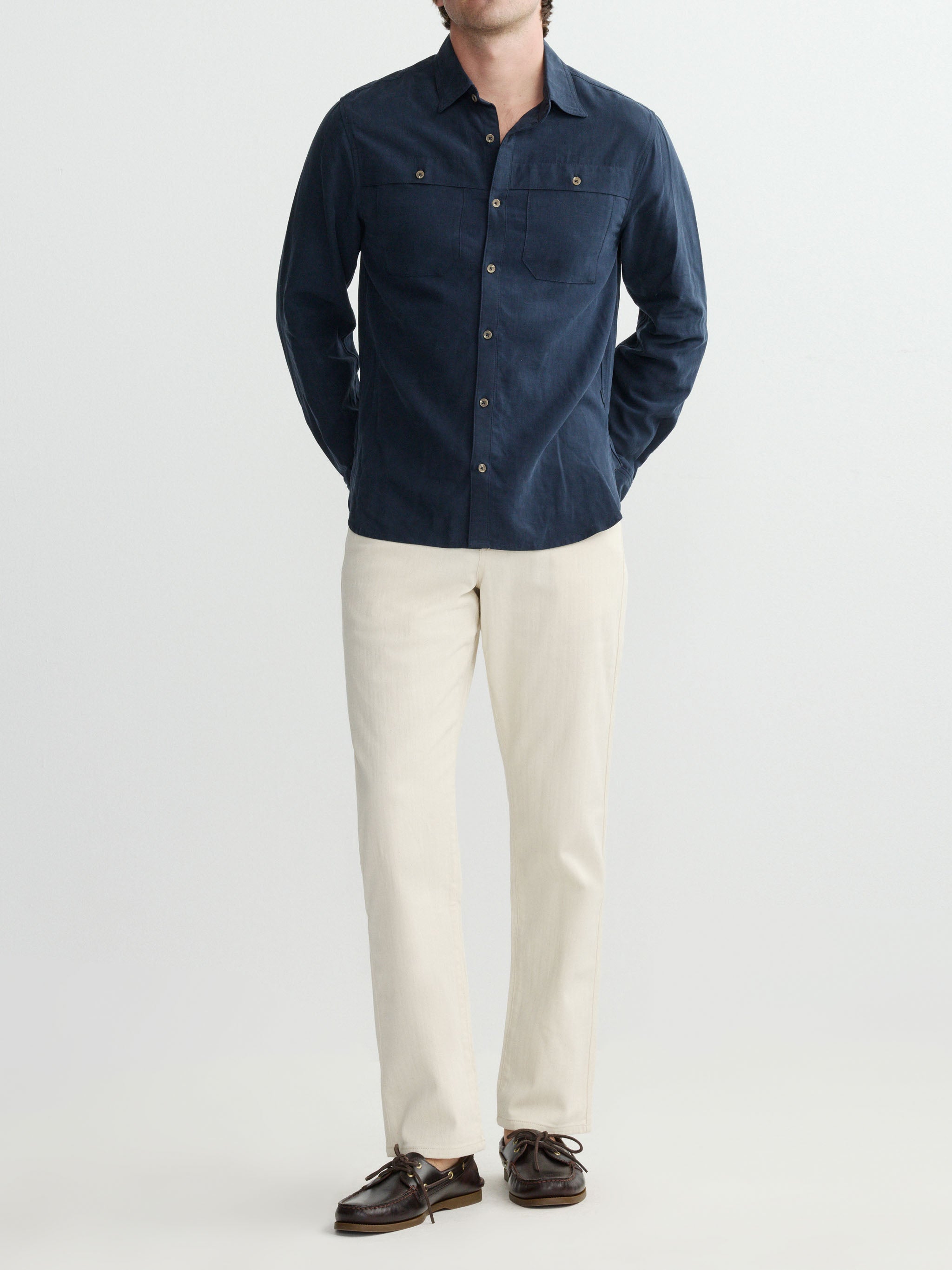 Person wearing a navy shirt and beige pants on a white background