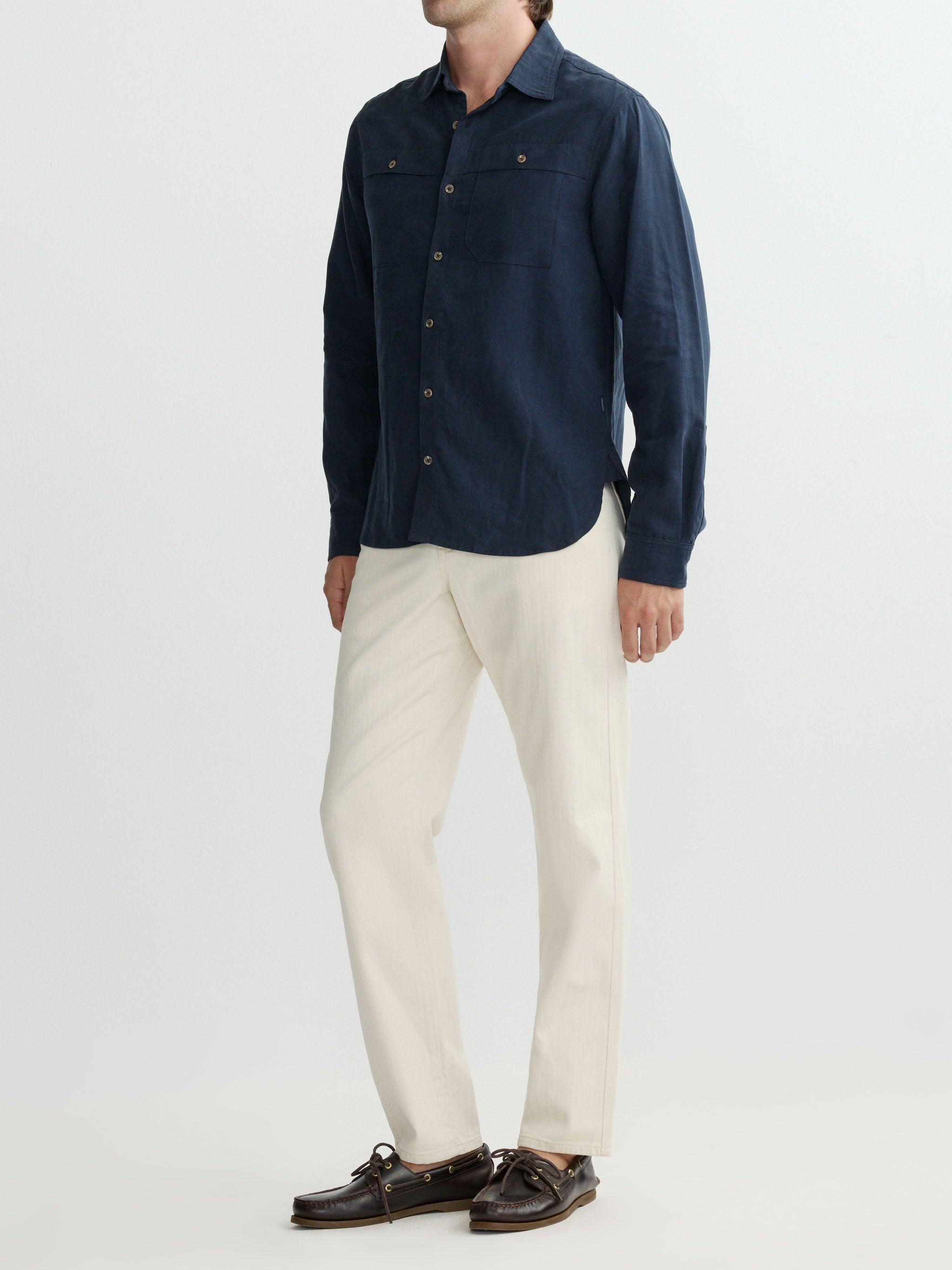 Person wearing a navy shirt and white pants on a light gray background