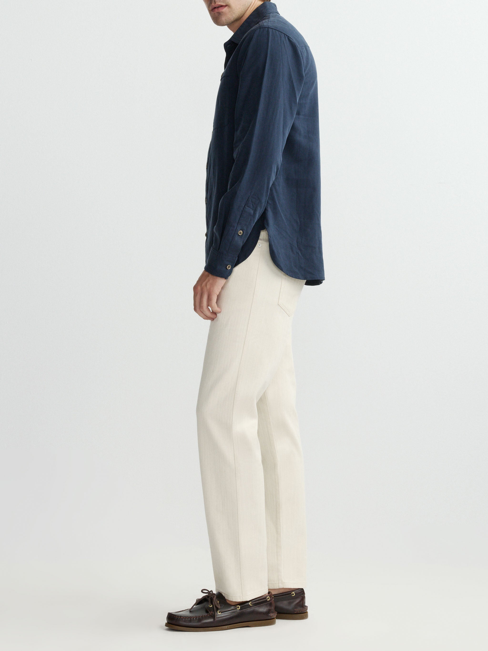Person wearing a navy shirt and white pants on a plain background