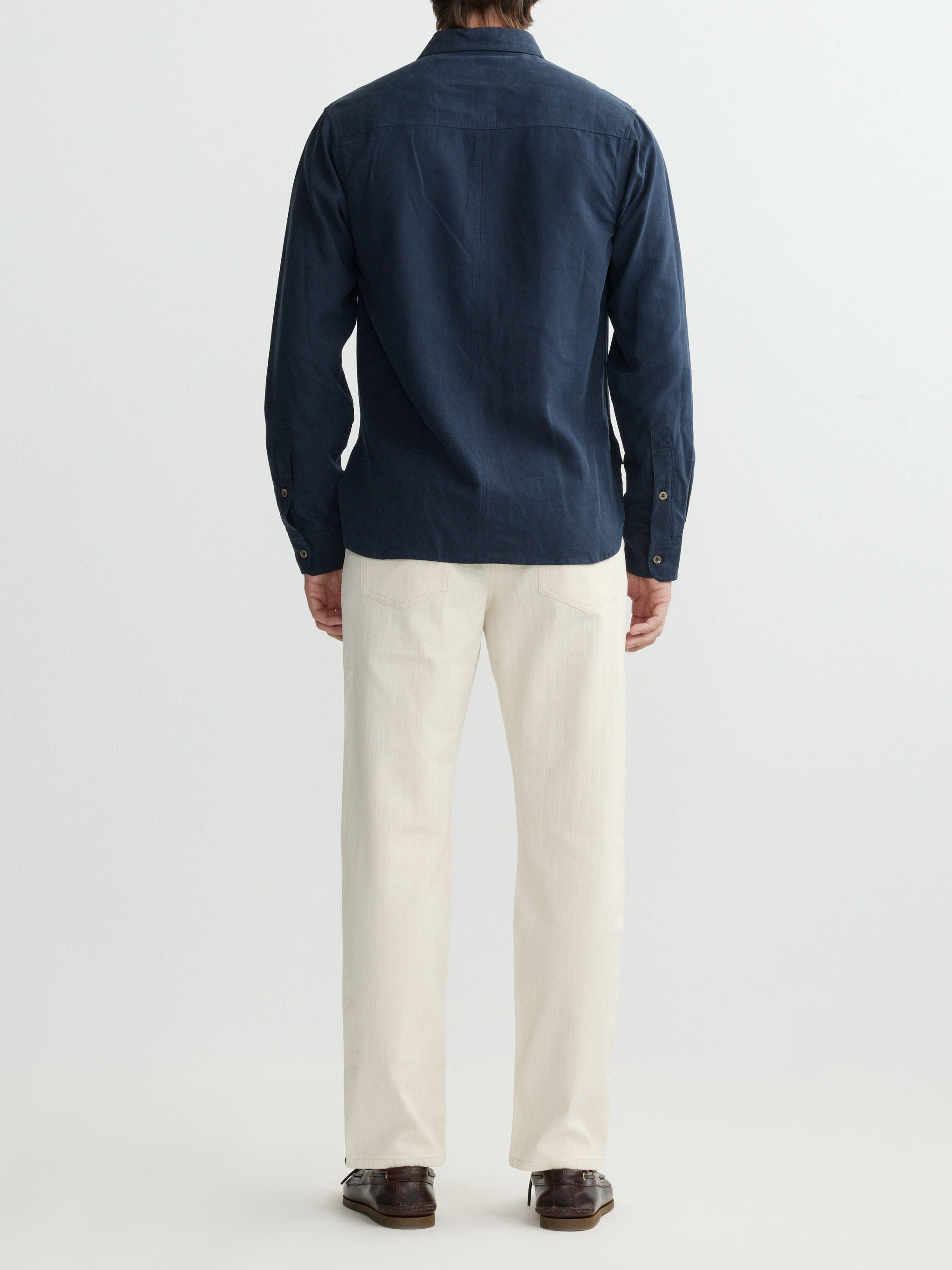 Person wearing a navy shirt and white pants on a light gray background
