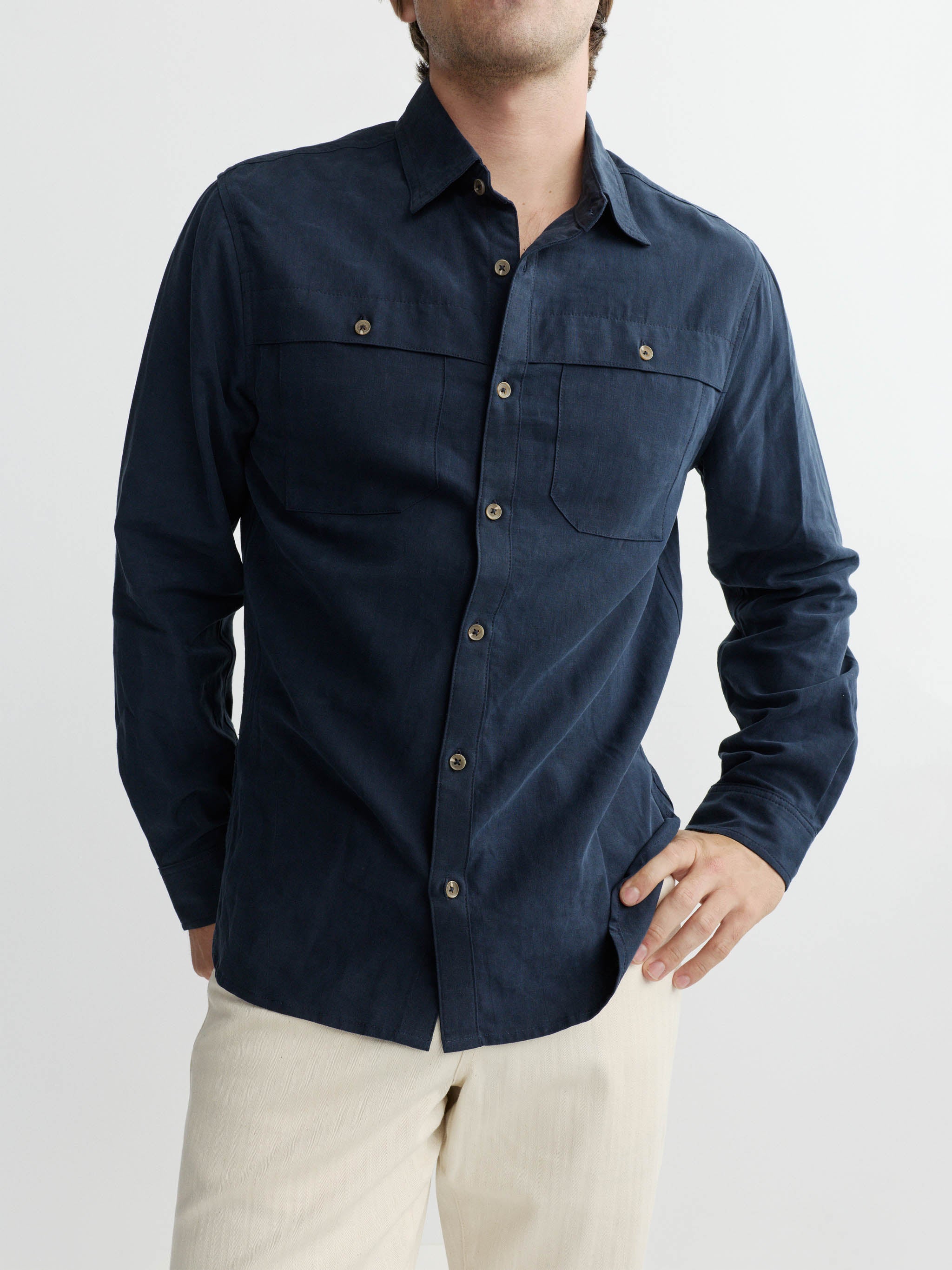 Man wearing a navy blue shirt with button details on a white background
