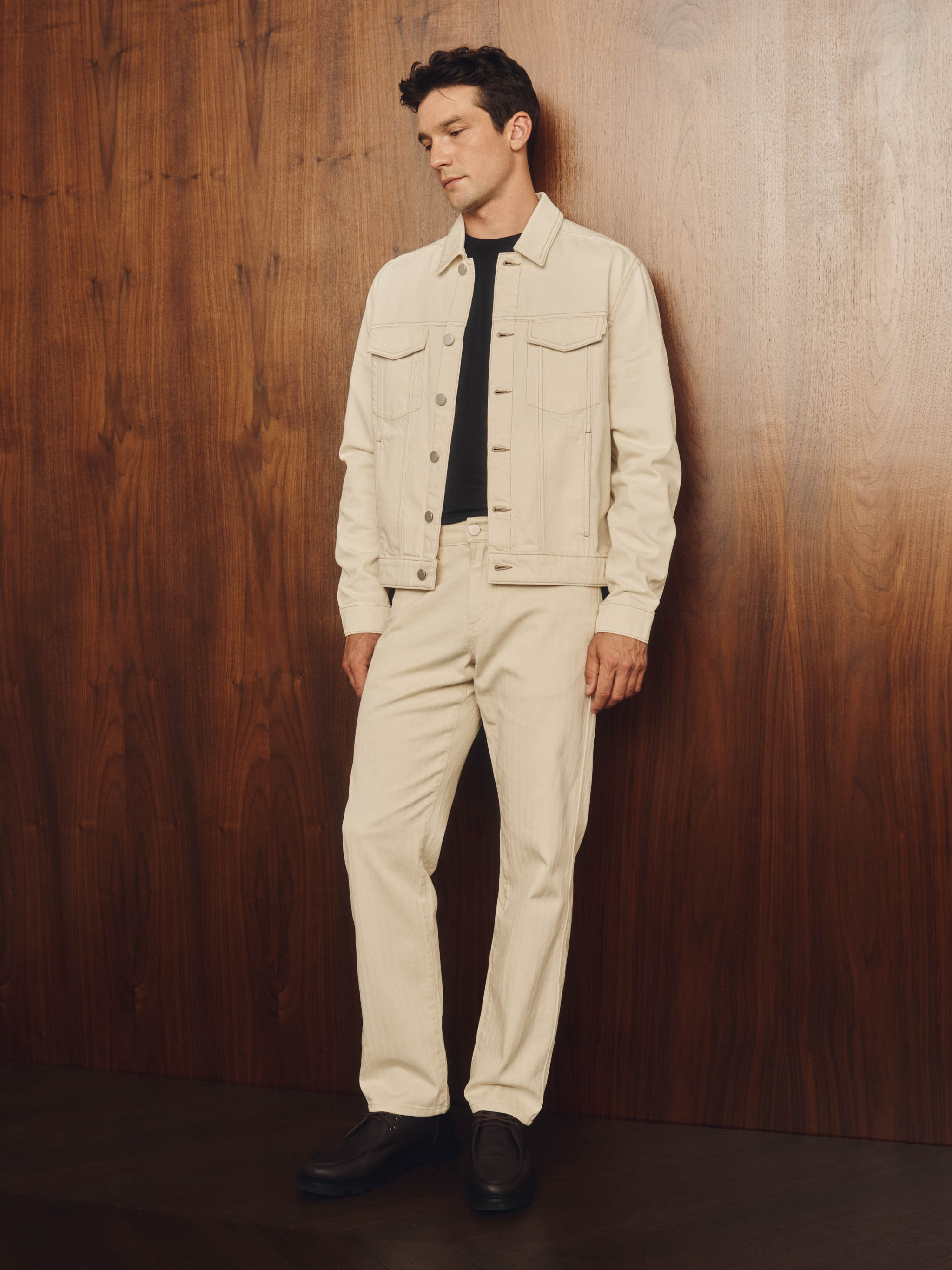 Person wearing a beige pants and jacket on a wood background
