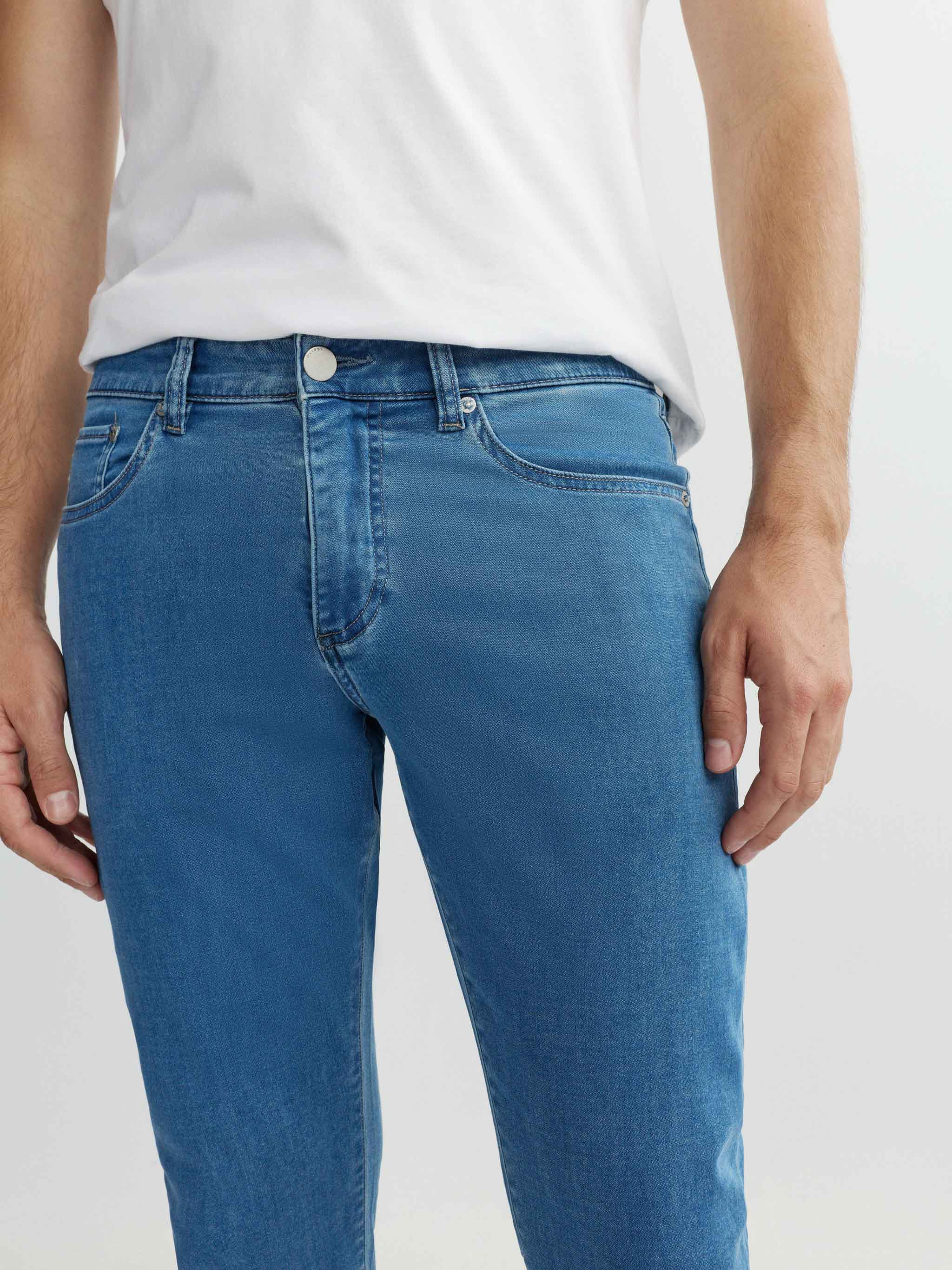 Person wearing blue jeans and a white shirt on a plain background