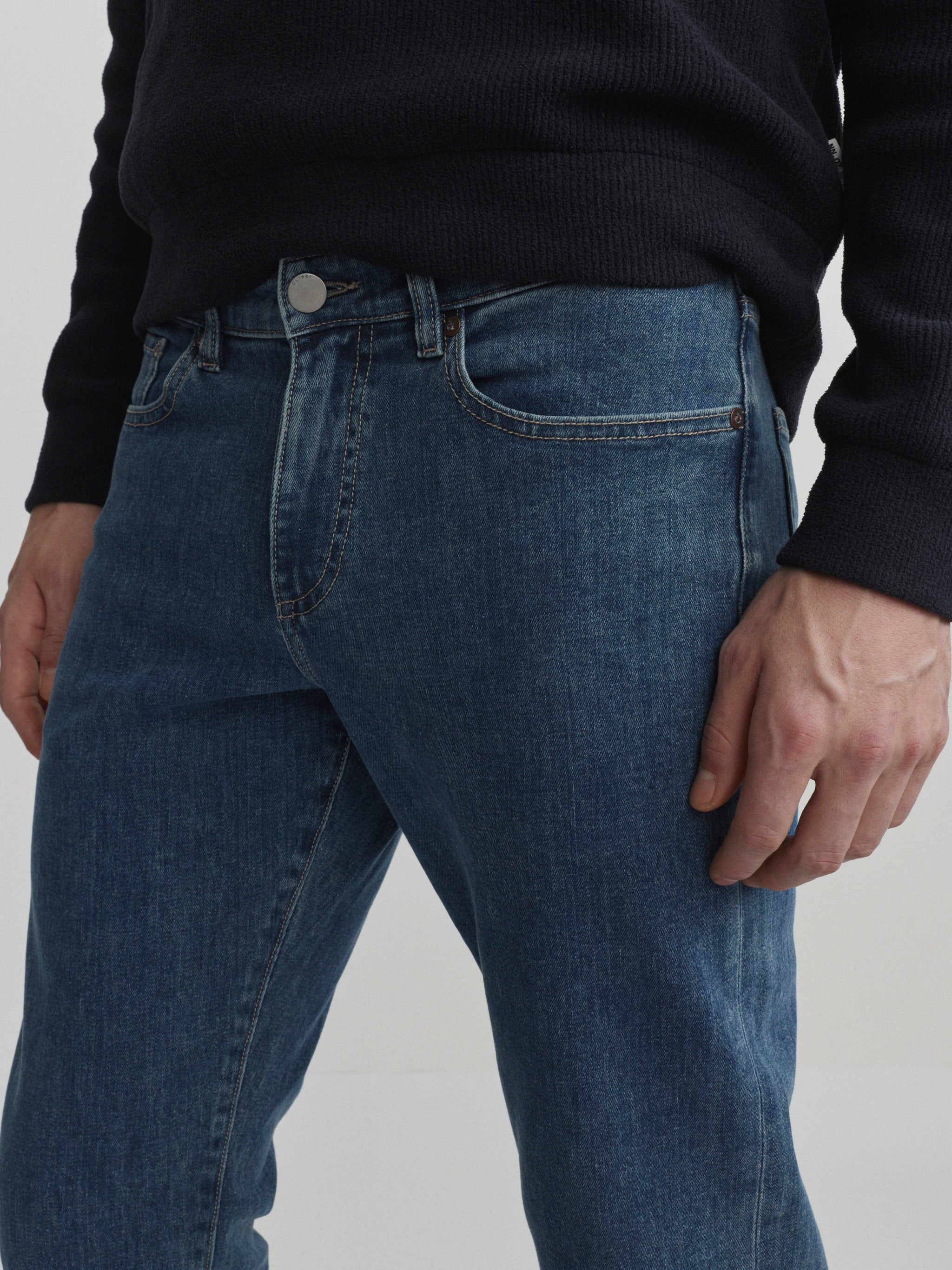 DL1961 men's Russell Slim Straight jeans in medium blue 'Highland Park', close-up of the front waist, button and pocket.